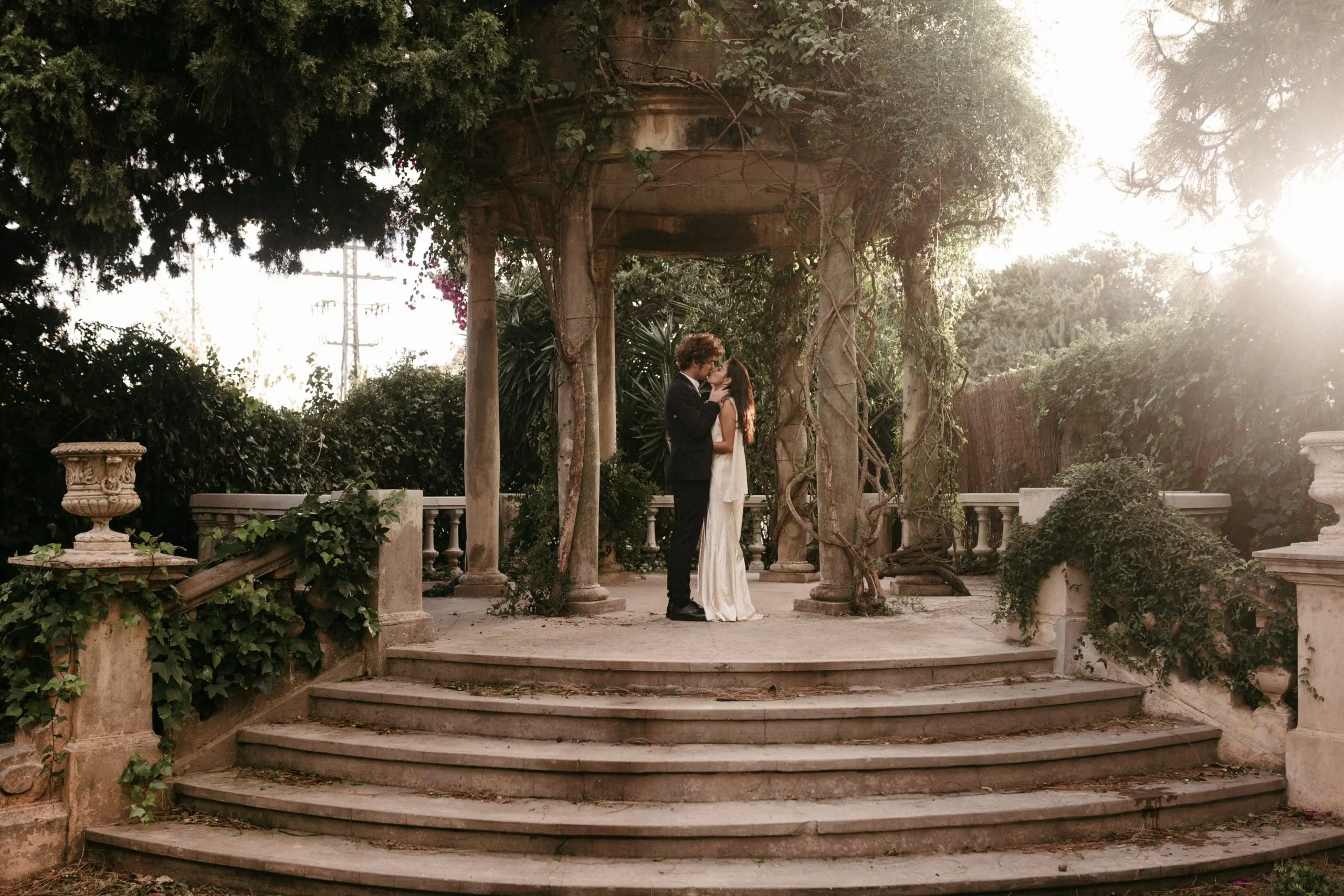 Novios besándose en el altar con un impresionante paisaje natural y el atardecer de fondo.