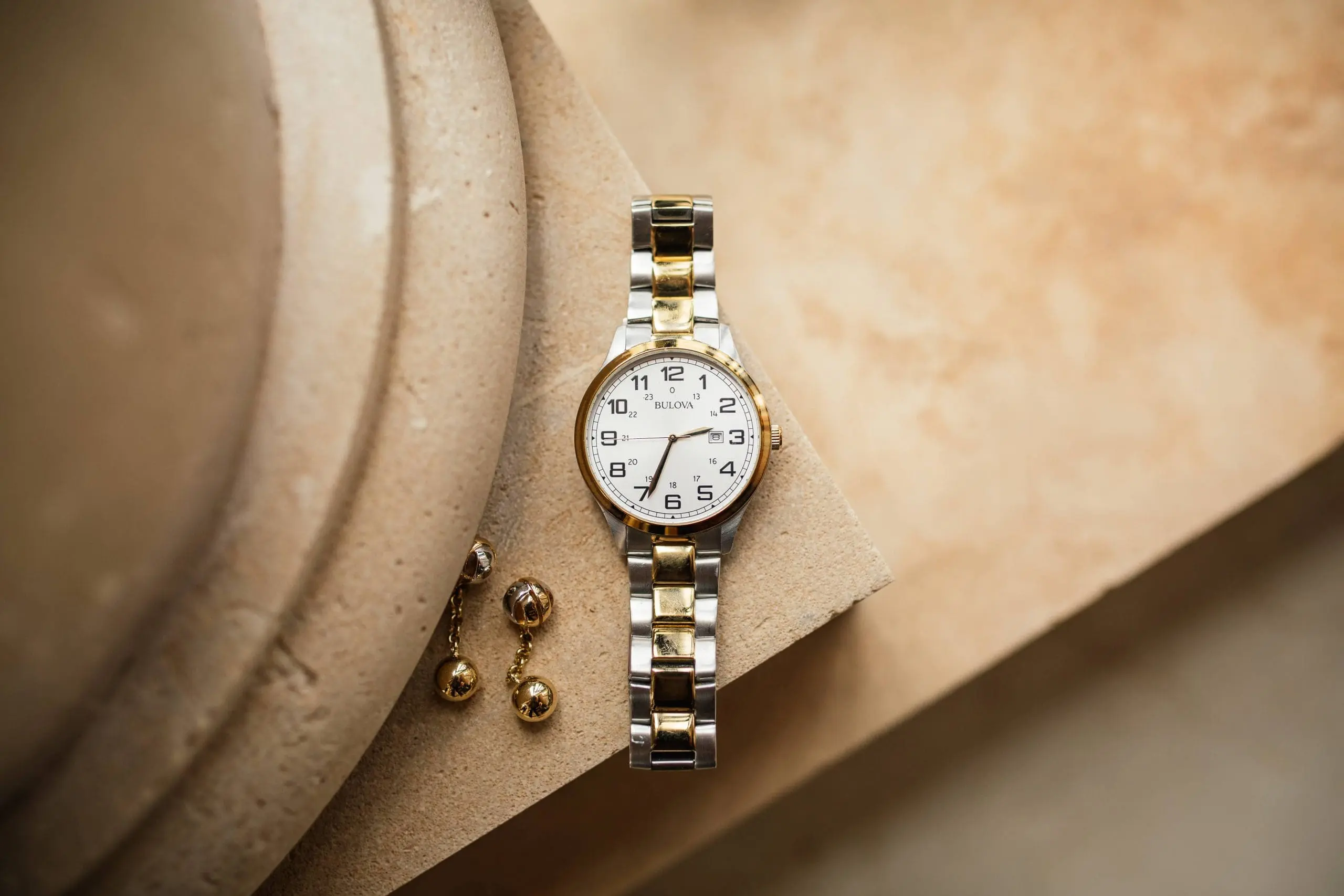 Detalles fotográficos de un reloj y unos gemelos de novio, reflejando la elegancia y la atención al detalle en los accesorios de boda.