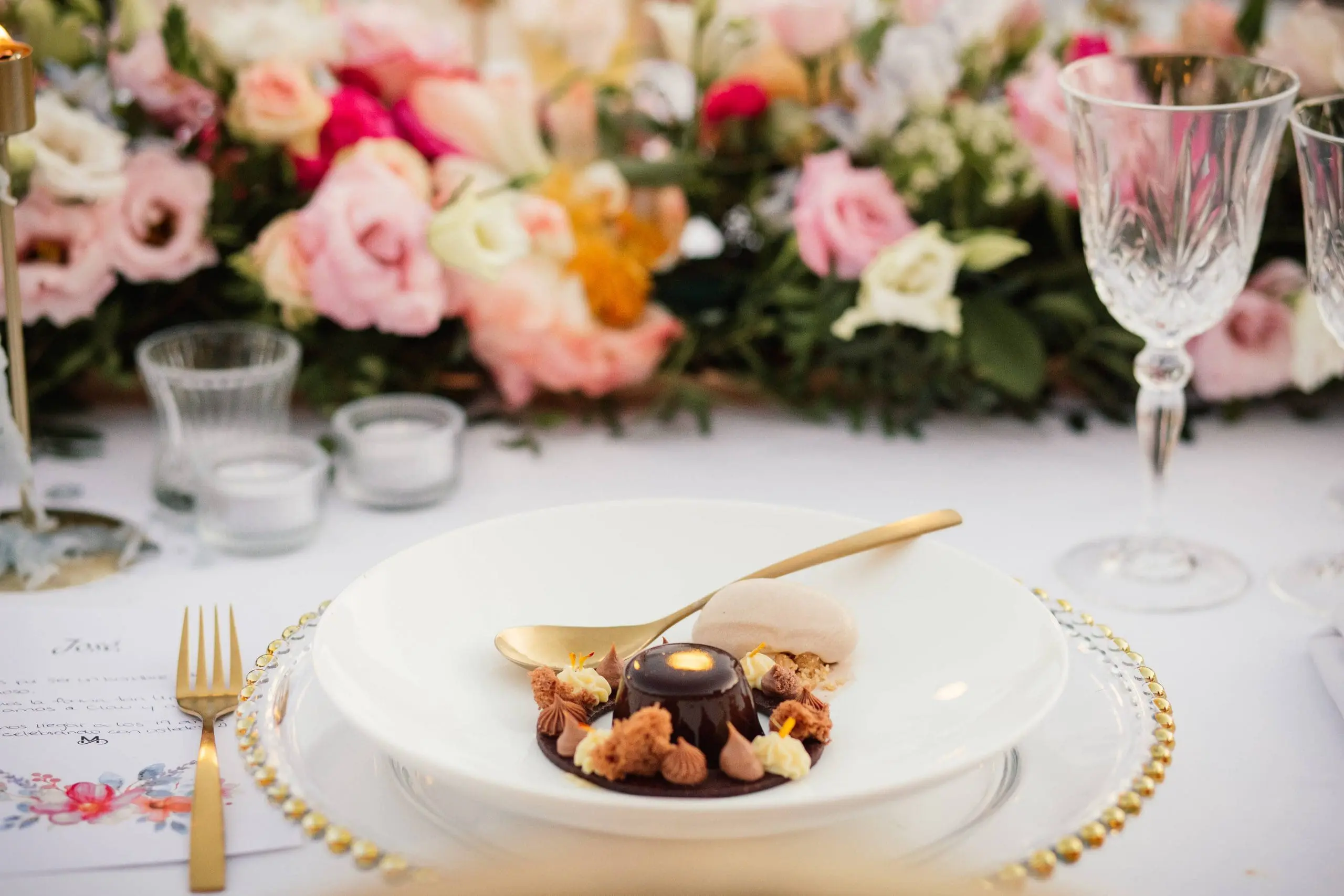 Mesa adornada por Bouclé Weddings para boda en Mallorca con el postre servido, con flores coloridas, cristalería brocada y cubertería dorada.