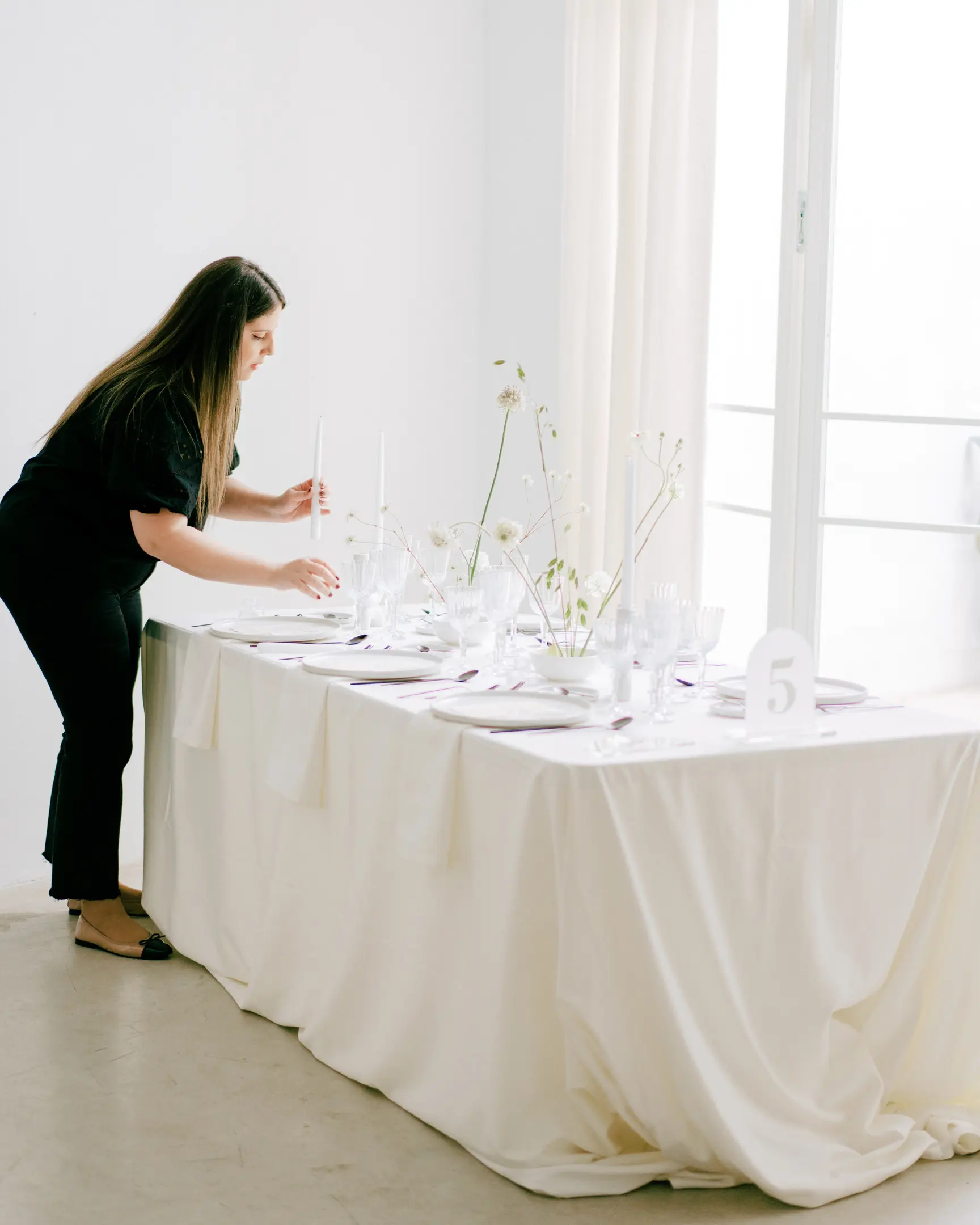 Estela from Bouclé Weddings designing a minimalist wedding table with simple floral decoration.