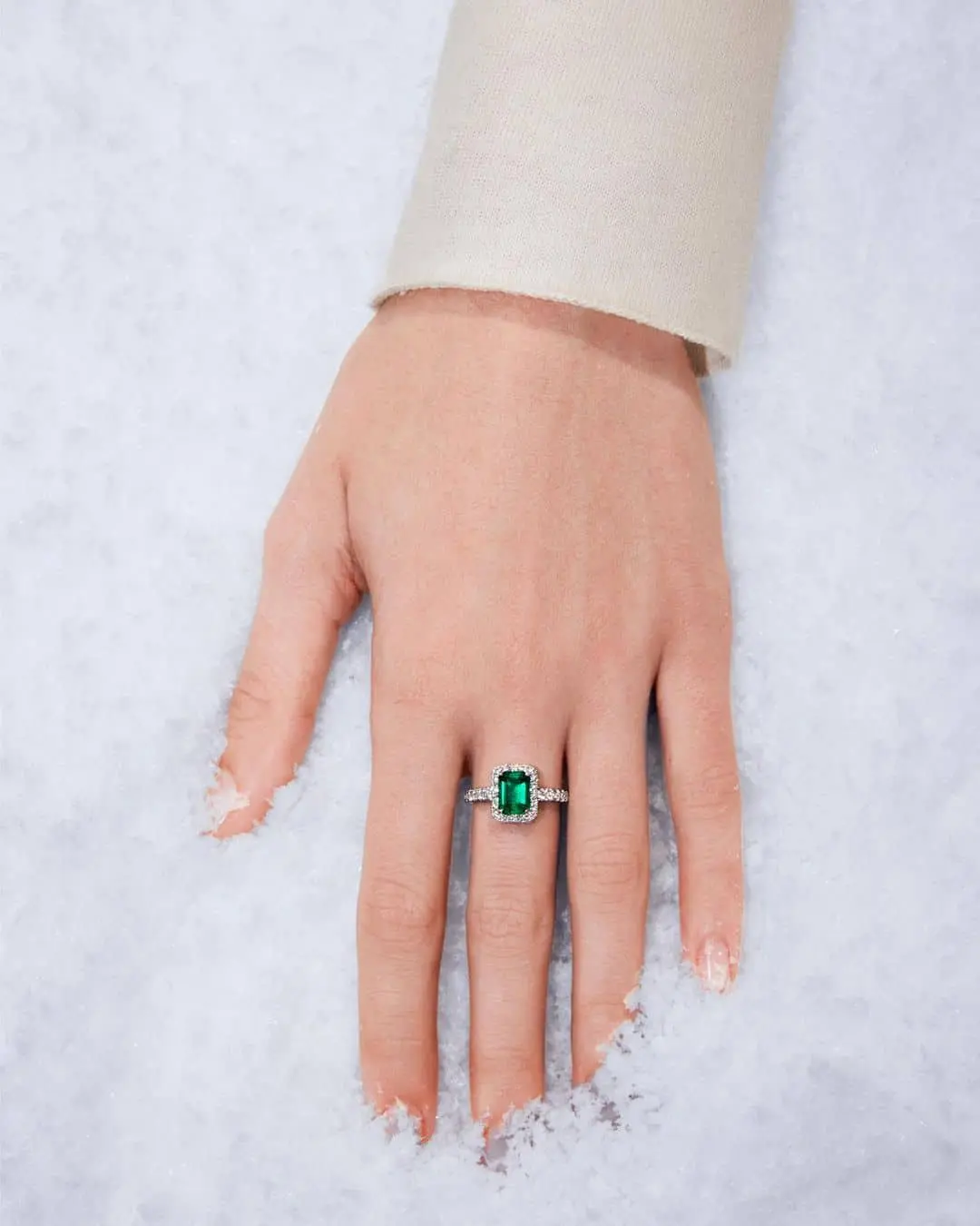 Mano luciendo un anillo de compromiso de Suárez con esmeralda