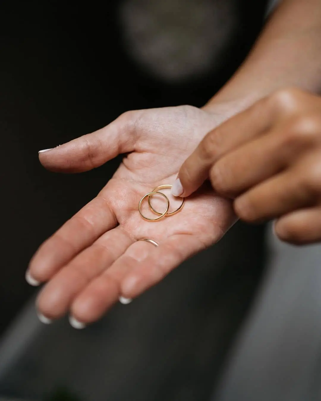 Palma de una mano sosteniendo dos alianzas de boda, simbolizando el compromiso y los votos matrimoniales.