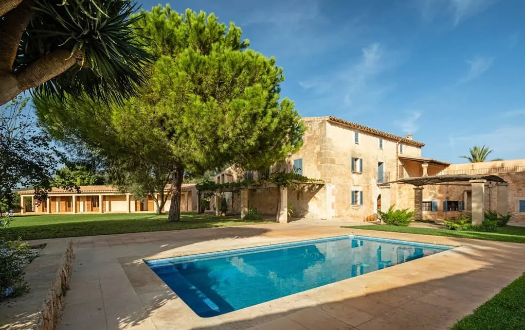 Piscina serena con la elegante Finca Son Sampol al fondo.