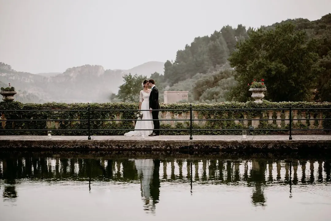 Romántico beso de una pareja de novios en Finca Comasema en Mallorca, junto a la piscina y con una panorámica de las montañas de fondo. Esta es una de las mejores fincas para bodas en Mallorca.