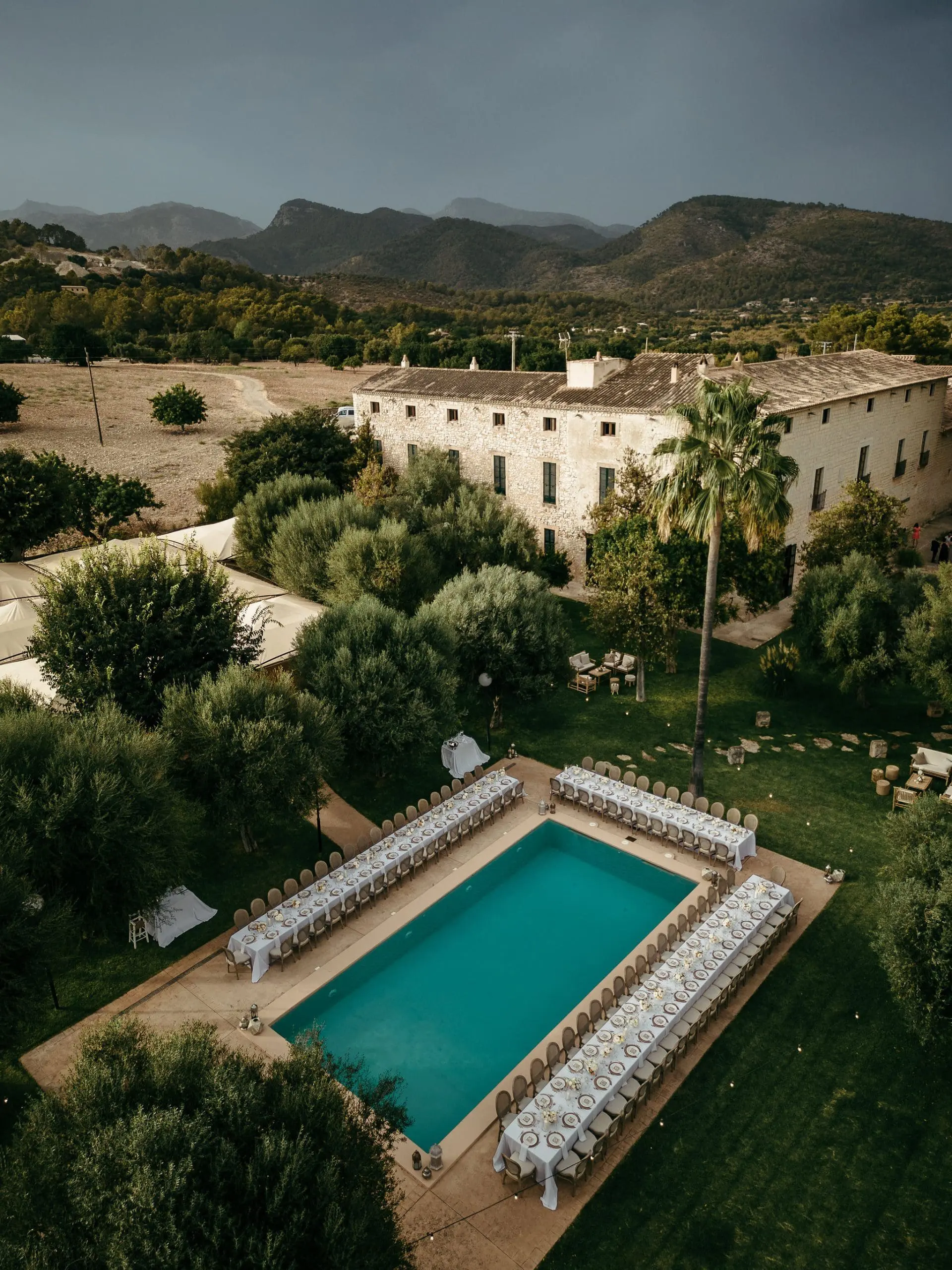 Vista aérea de Finca Morneta con mesas y sillas dispuestas alrededor de la piscina en una boda. Esta es una de las mejores fincas para bodas en Mallorca.
