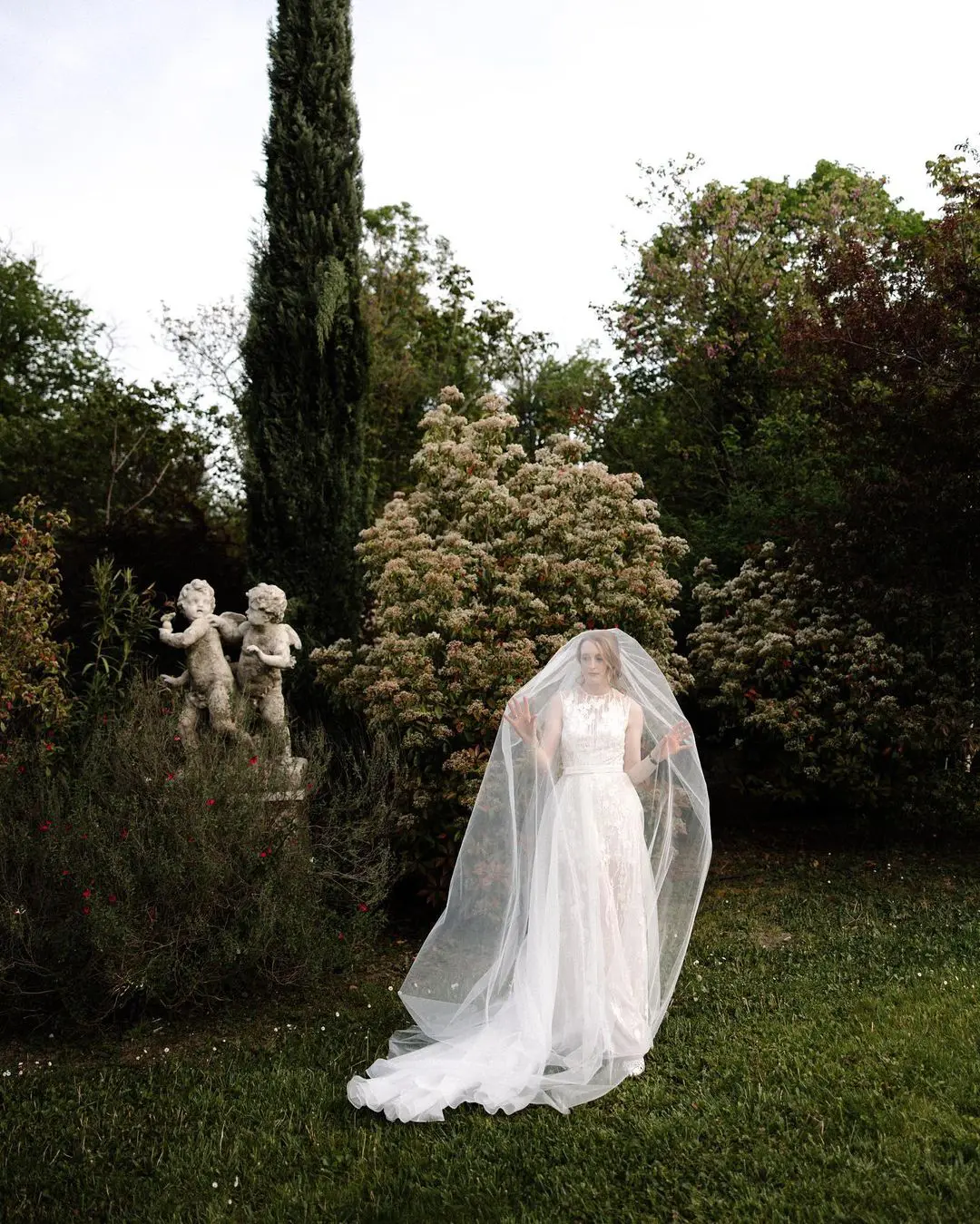 Novia con velo radiante en un jardín exuberante, esencial en un kit de emergencia para bodas al aire libre.