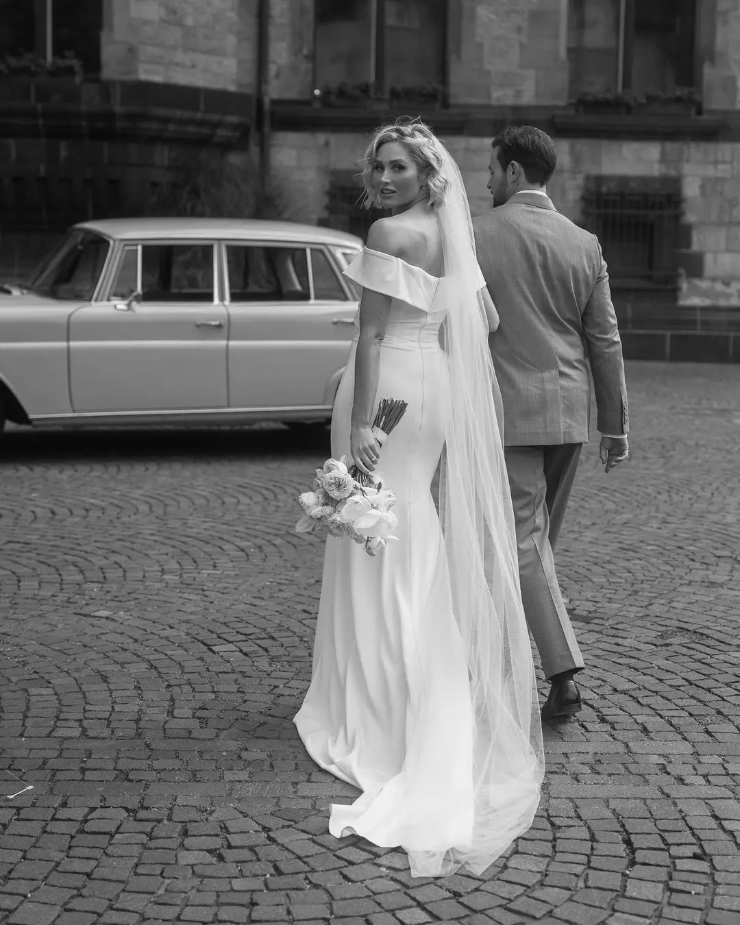 Pareja de novios caminando de la mano por una calle adornada, simbolizando el camino compartido en el matrimonio