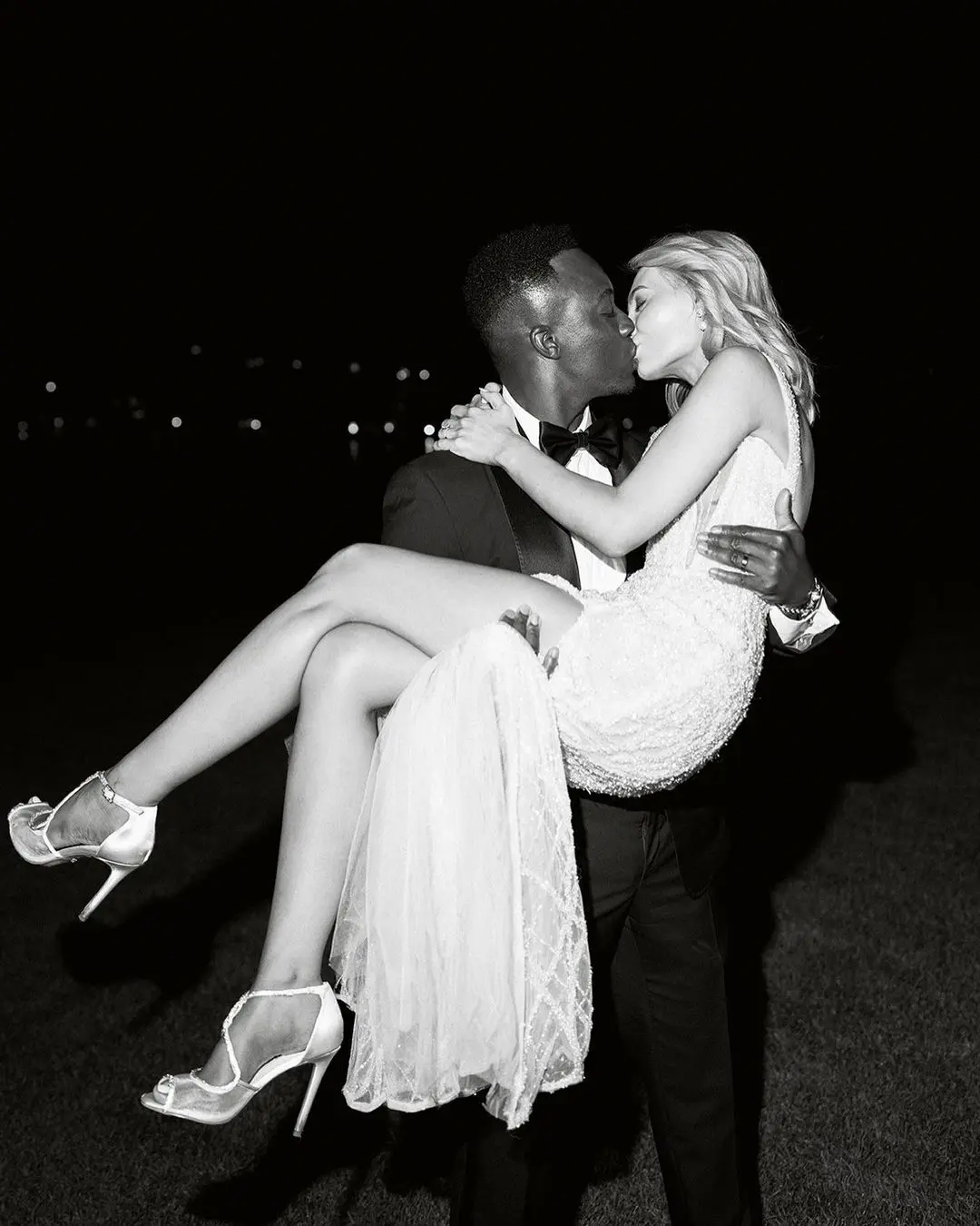 A groom holding his bride in his arms and kissing her, symbolizing one of the best wedding dates according to astrology in 2025.