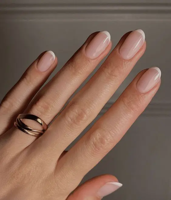 Detalle de uñas estilo Baby French, ideales para una boda, con base rosada y línea blanca sutil.
