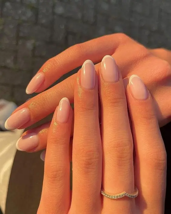 Primer plano de uñas estilo Baby French para novia, con base rosada discreta y línea blanca fina.