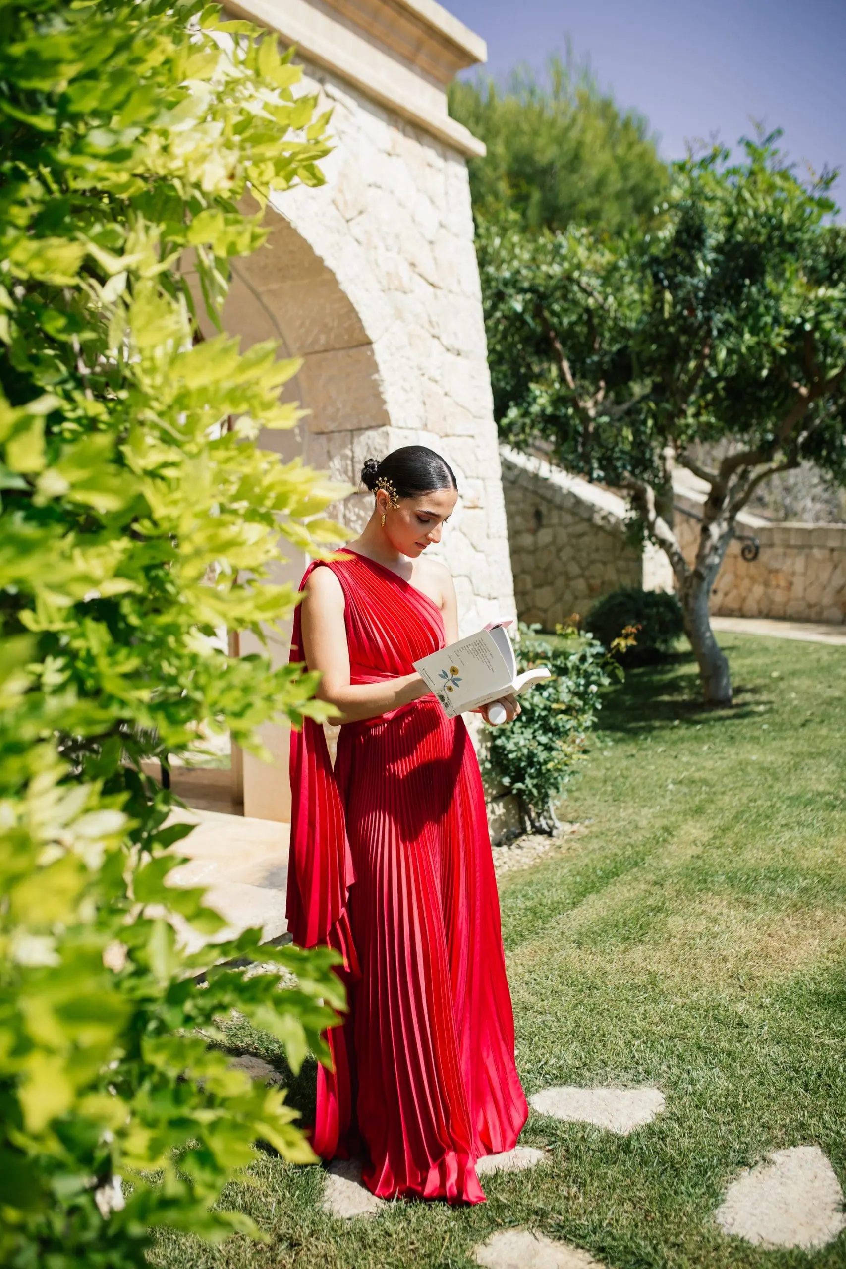 Invitada leyendo un libro en los jardines de Cap Vermell Grand Hotel, Mallorca, durante una boda íntima.