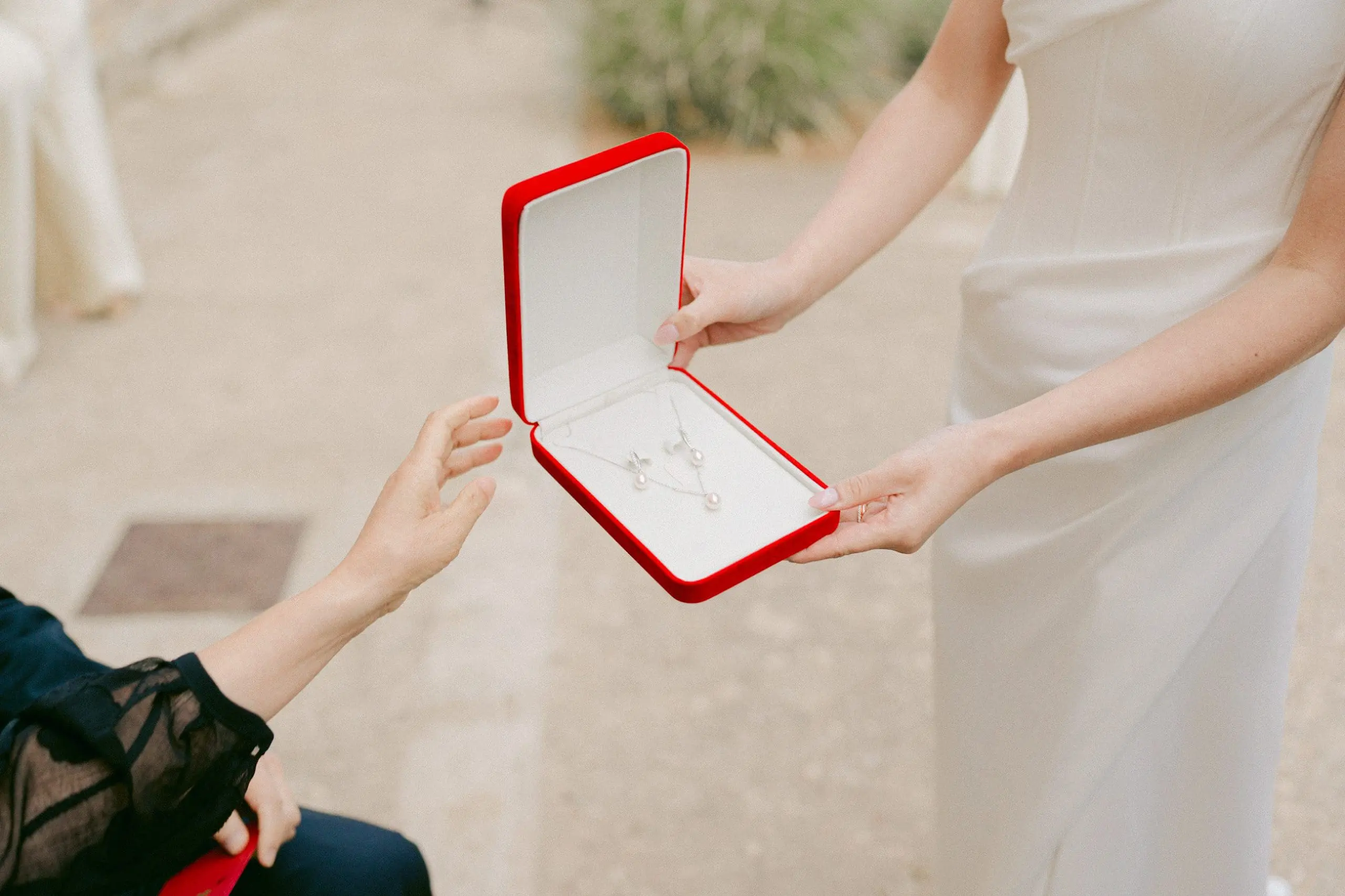 Invitado sentado entregando un regalo a la novia durante la ceremonia del té en una boda china.
