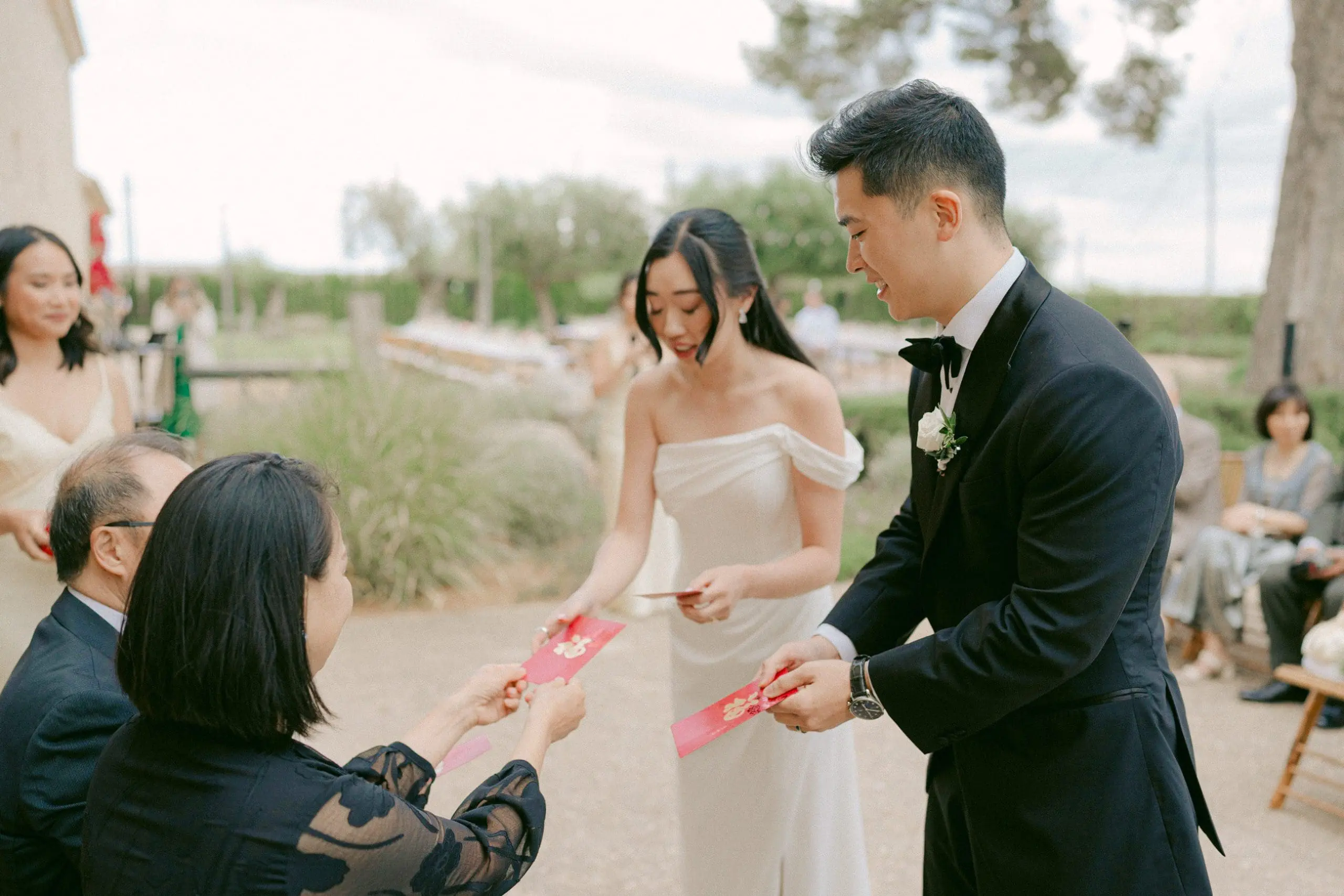 Padres de los novios entregando un sobre rojo a los novios durante la ceremonia del té en una boda china.