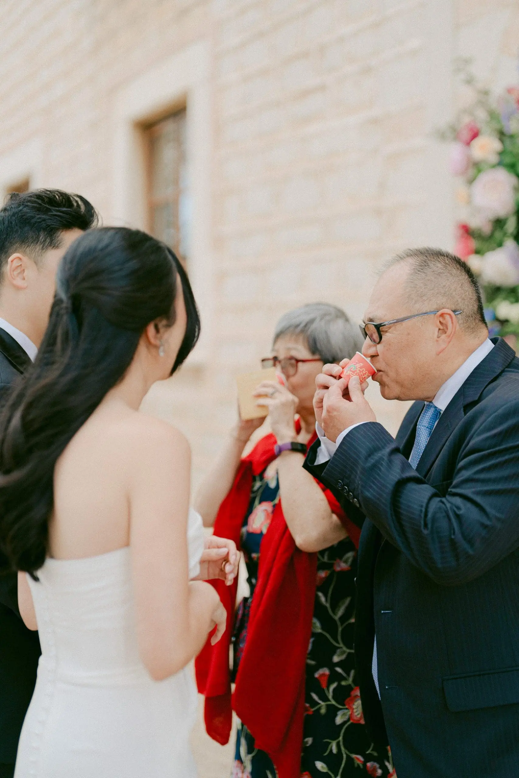 Padres de la novia bebiendo el té ofrecido por los novios durante la ceremonia del té en una boda china.
