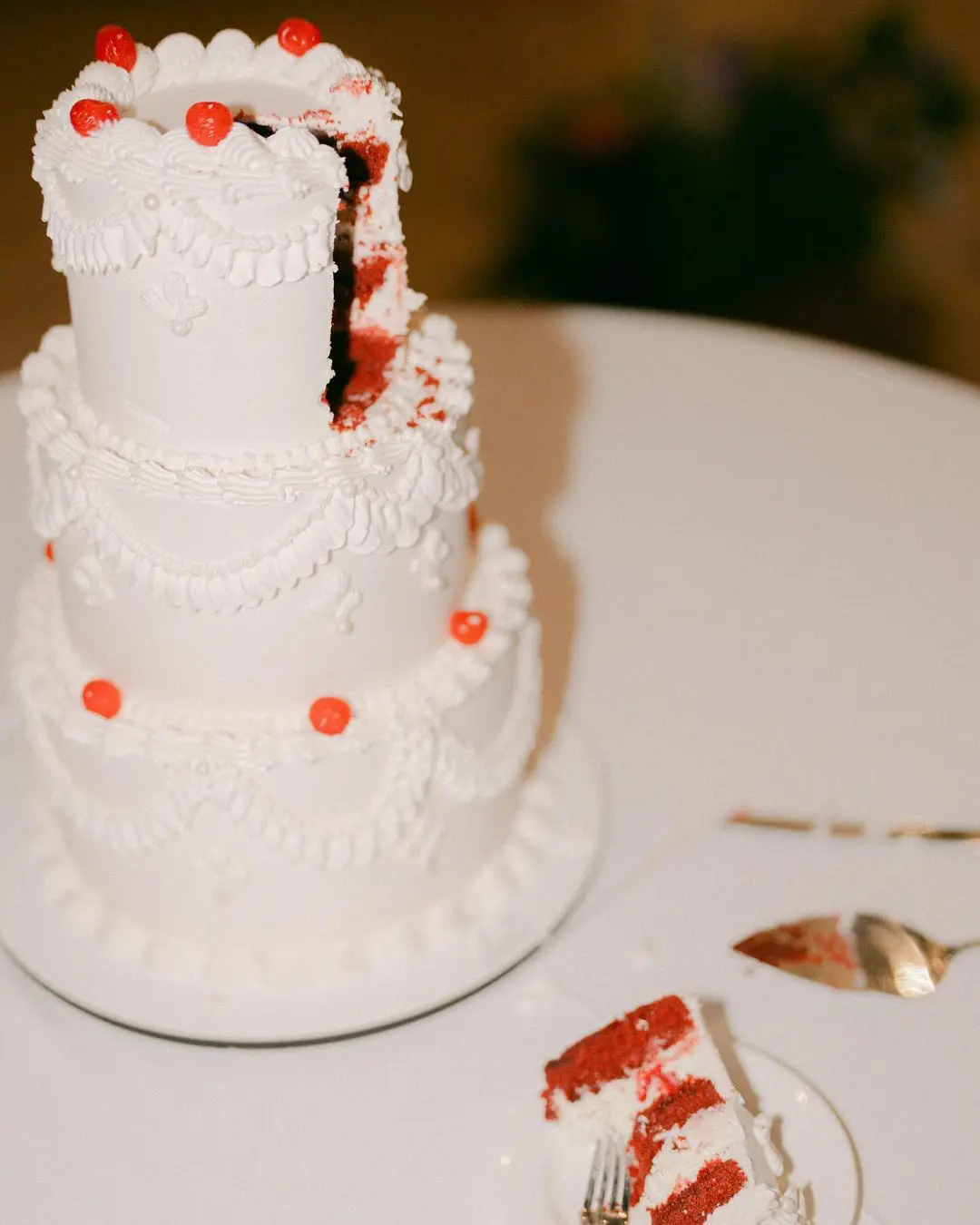Tarta de bodas blanco con un trozo cortado, revelando un relleno de color rojo, simbolizando el hilo rojo del destino.
