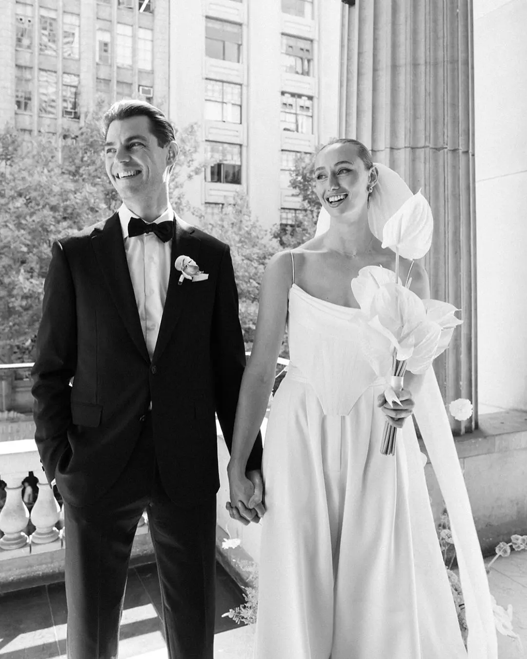 Pareja recién casada posando en fotos de boda, ambos sonrientes y tomados de la mano.