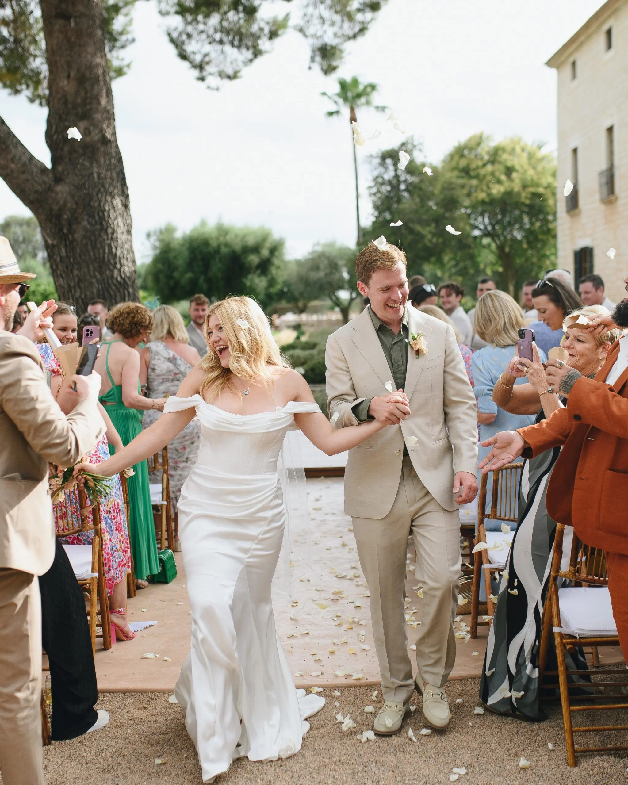 Recién casados celebrando su boda al aire libre mientras los invitados les lanzan pétalos