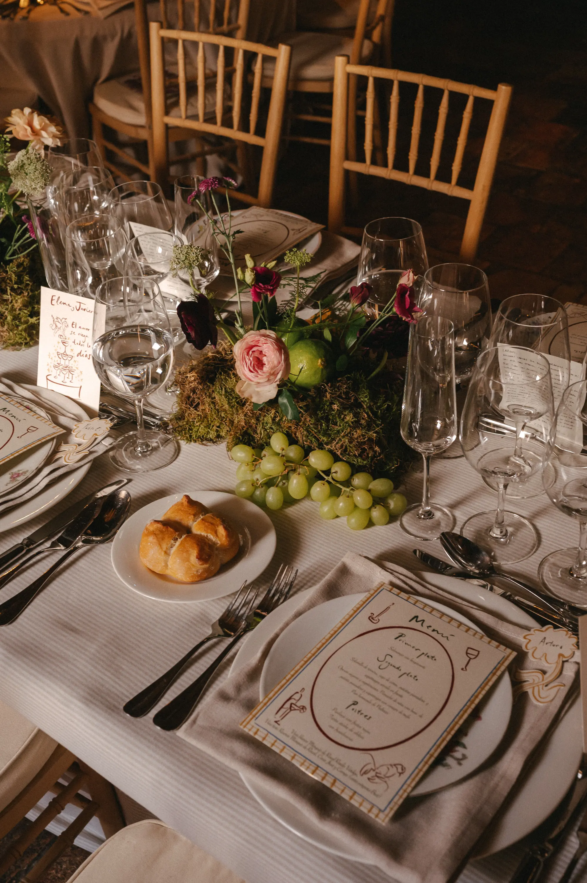 Centro de mesa de boda con musgo, frutas como uvas y limas, y velas, reflejando las tendencias de boda 2025.