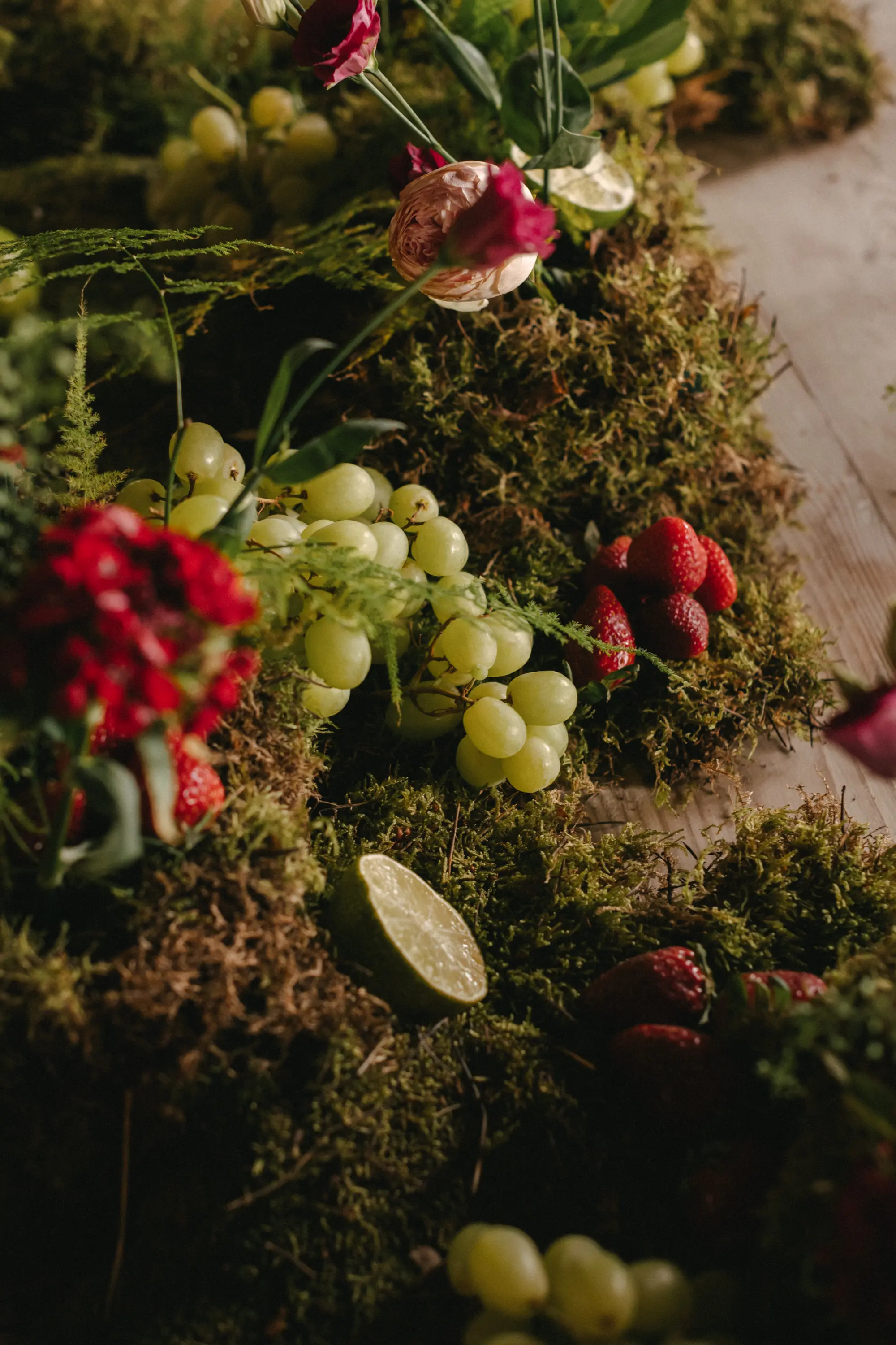Decoración de boda con musgo, uvas y limas como centro de mesa, siguiendo las tendencias de boda 2025.