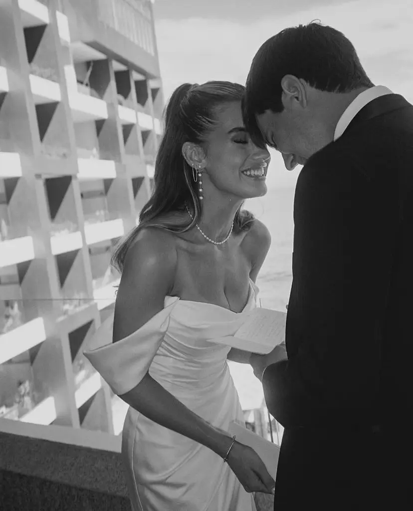 Novia y novio intercambiando votos con emoción en un espacio al aire libre con vista al mar.
