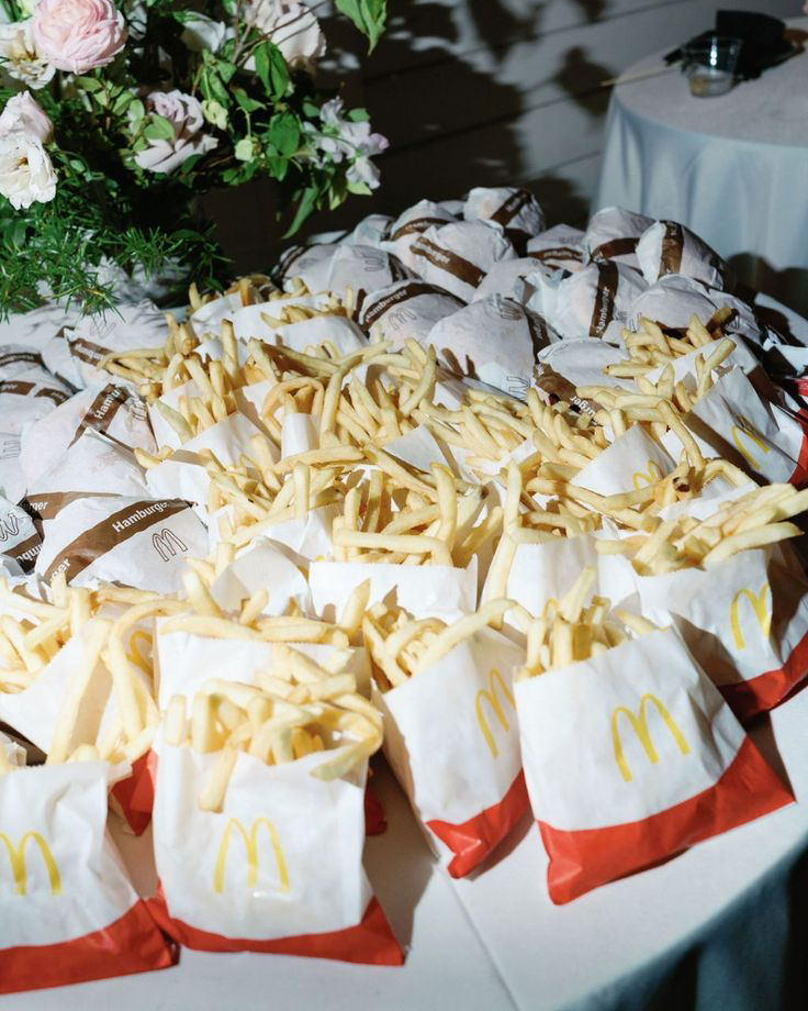 Mesa con hamburguesas y patatas fritas en envases individuales del McDonald's, una opción informal para la recena de boda.
