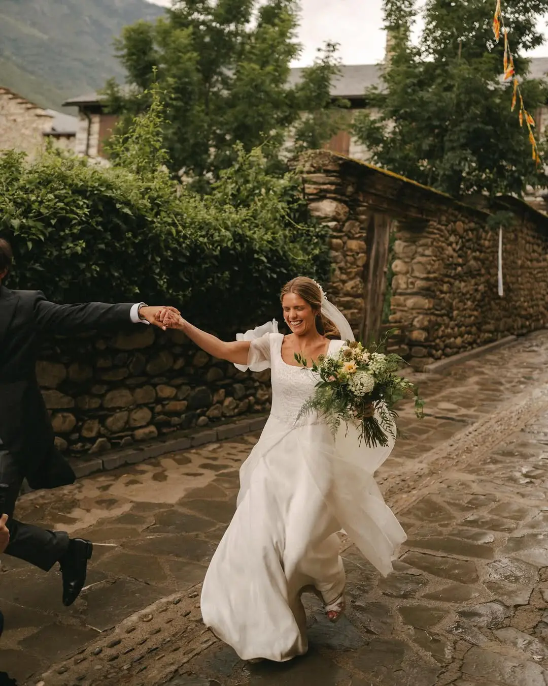 Novia sonriente corriendo por una calle empedrada tras la ceremonia.