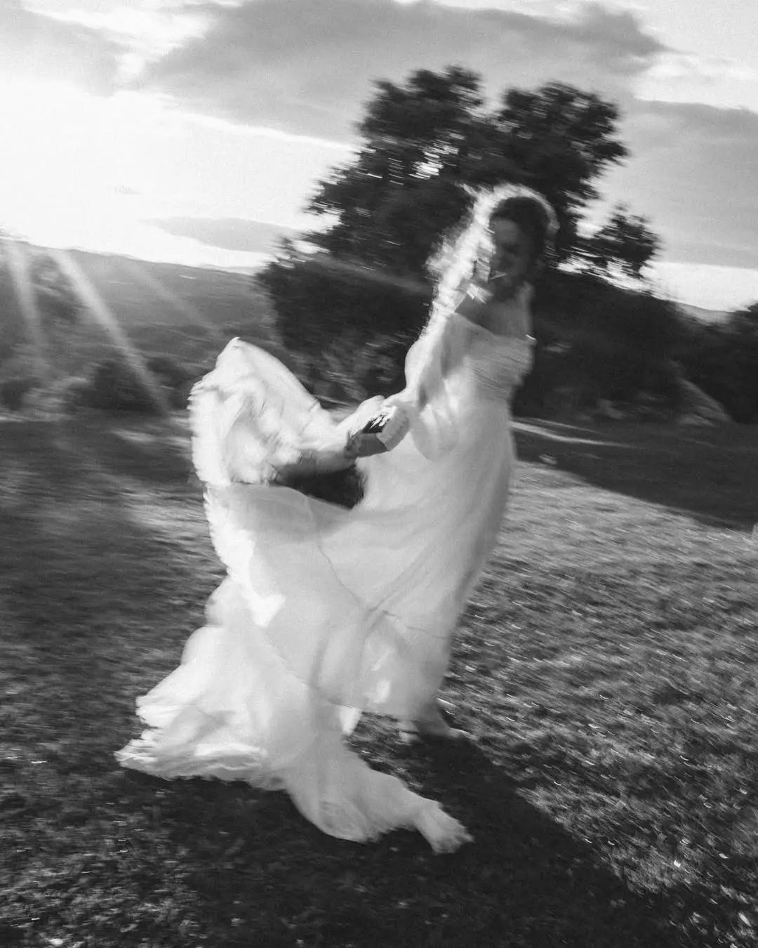 Novia girando con su vestido en un campo al atardecer.