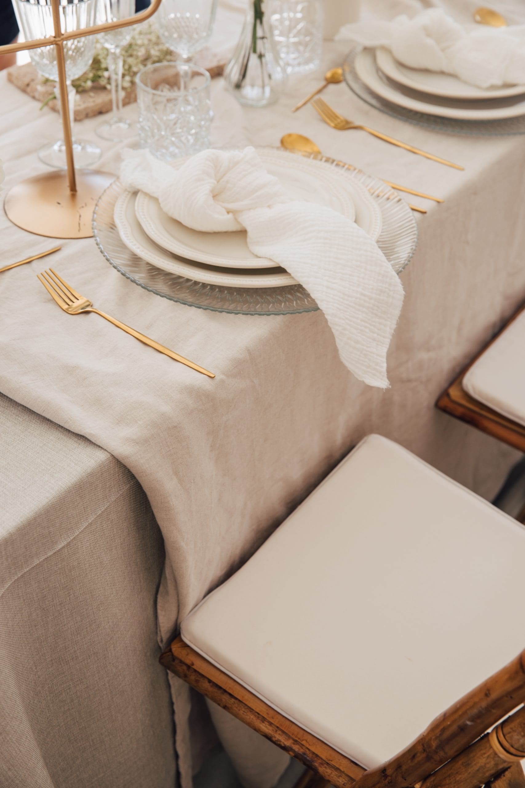 Decoración de mesa de boda elegante y clara con servilletas y vajilla dorada.