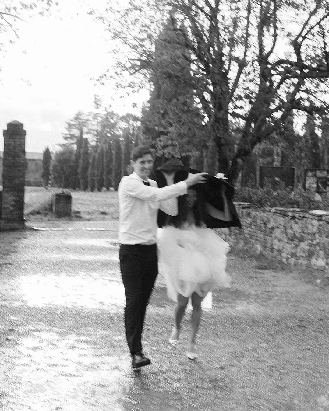 Novio protege a la novia con su chaqueta en un día lluvioso de boda.