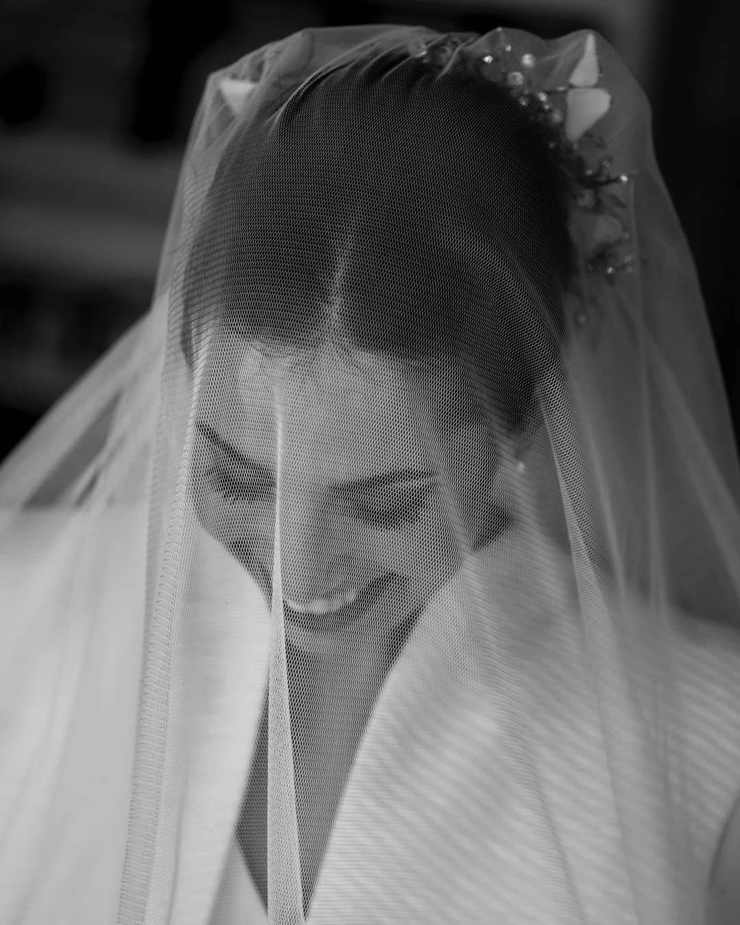 Novia con velo puesto, sonriendo y luciendo feliz durante el rito de la velación.