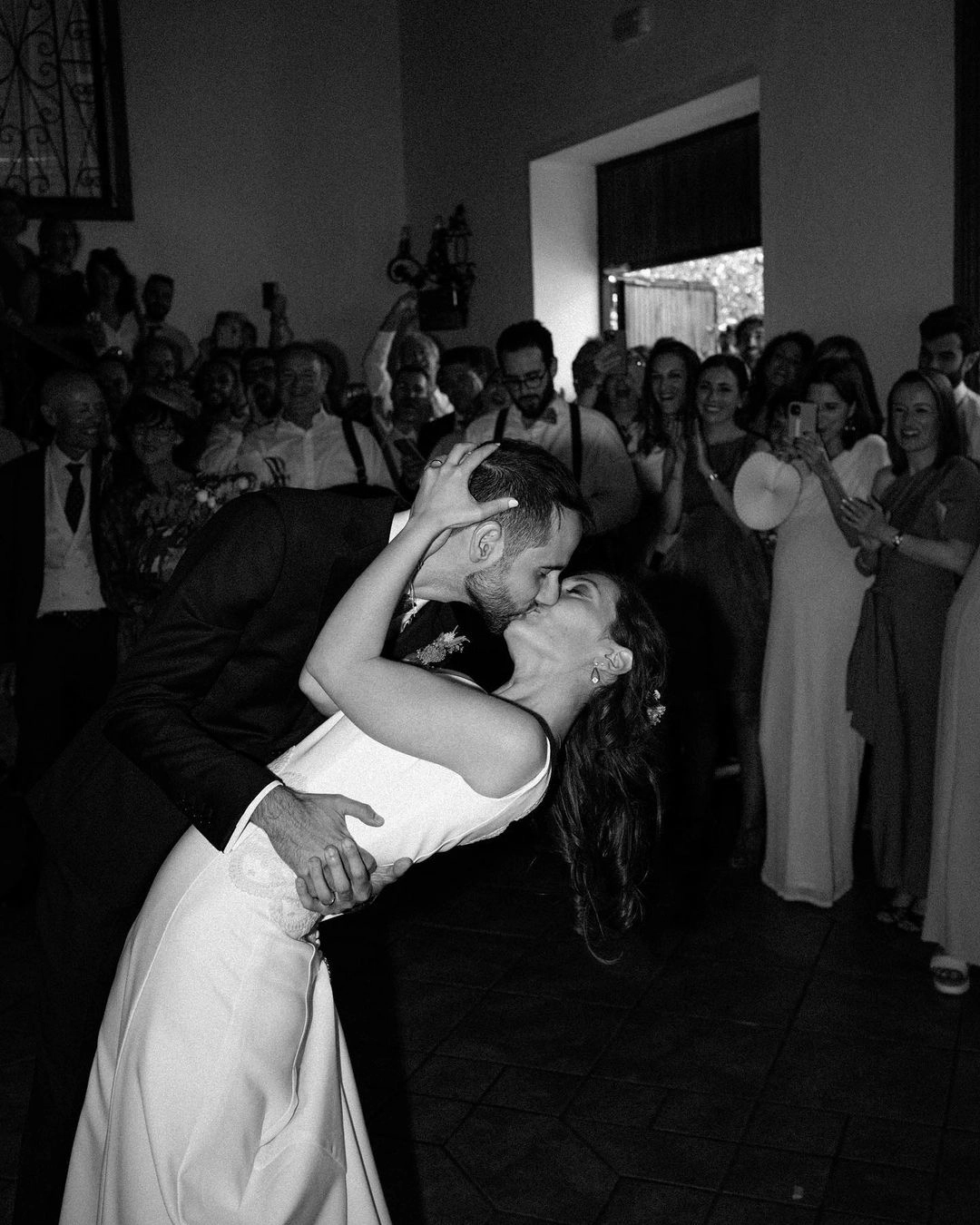 Novios compartiendo un apasionado beso en el altar, mientras los invitados aplauden en celebración de sus votos de boda.