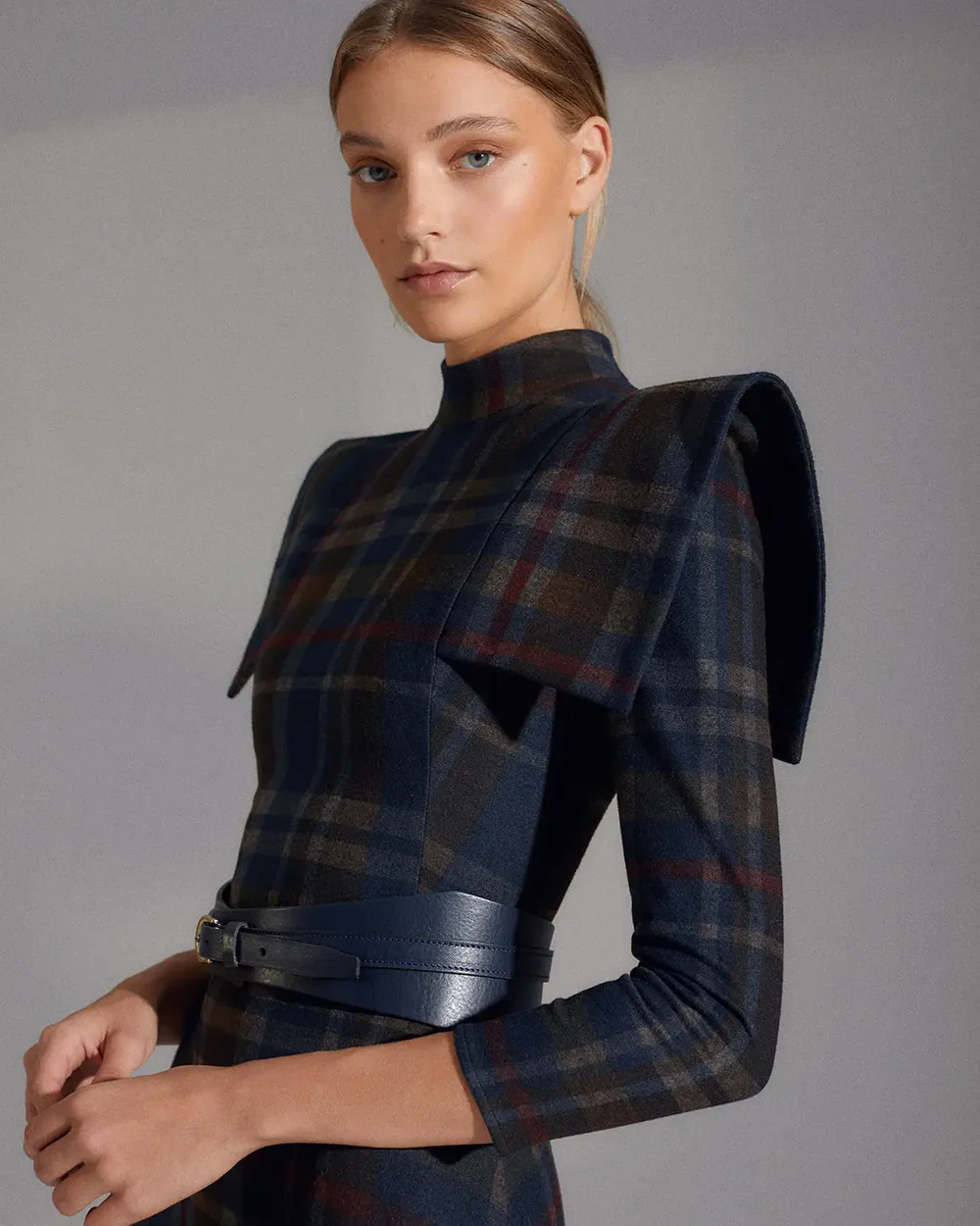 Detalle de las hombreras cuadradas y el estampado tartán azul del vestido de The IQ Collection.