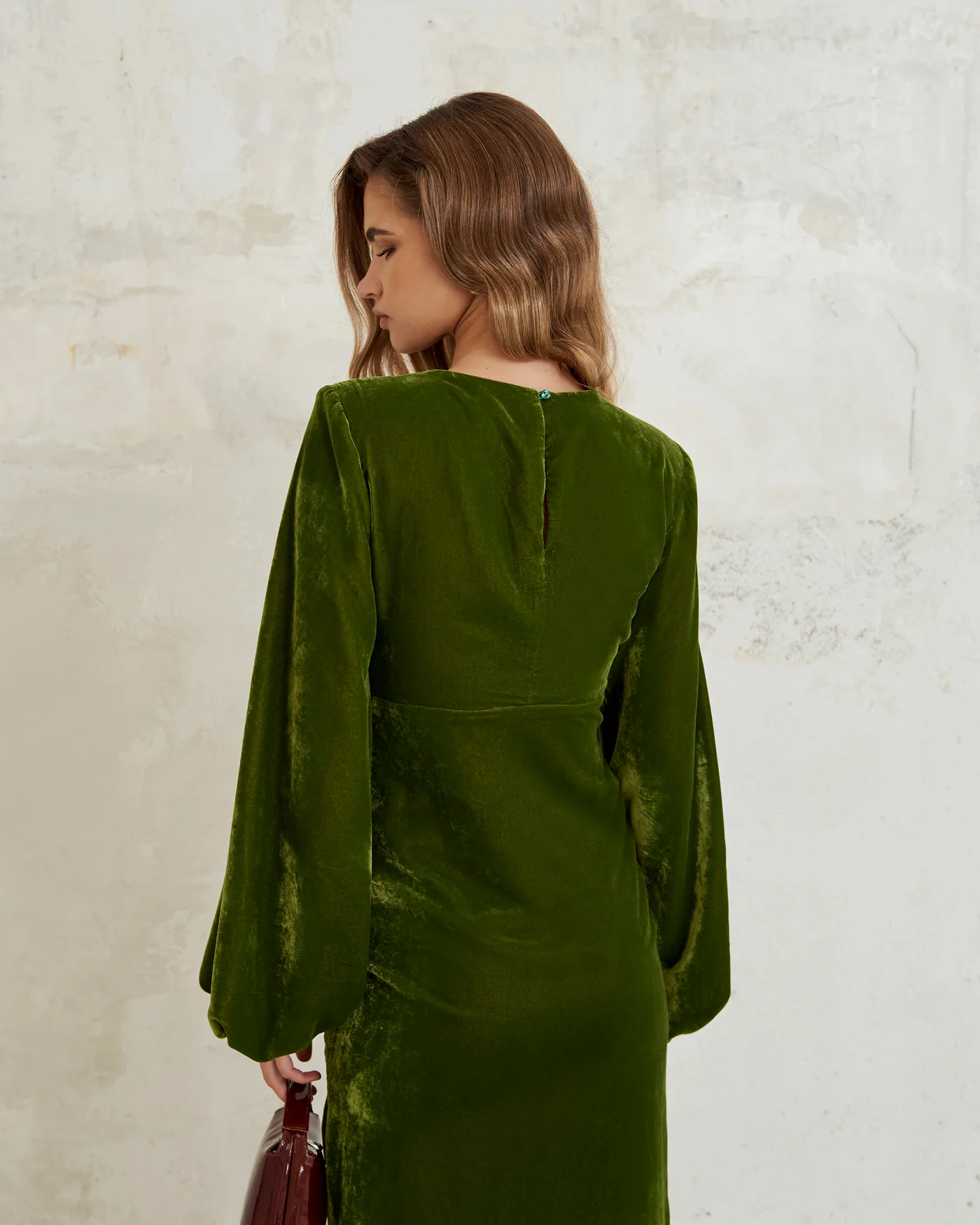 Vista trasera del Vestido Florida Oliva de Lady Pipa, mostrando su diseño elegante en terciopelo con abertura lateral y detalle de manga abullonada.