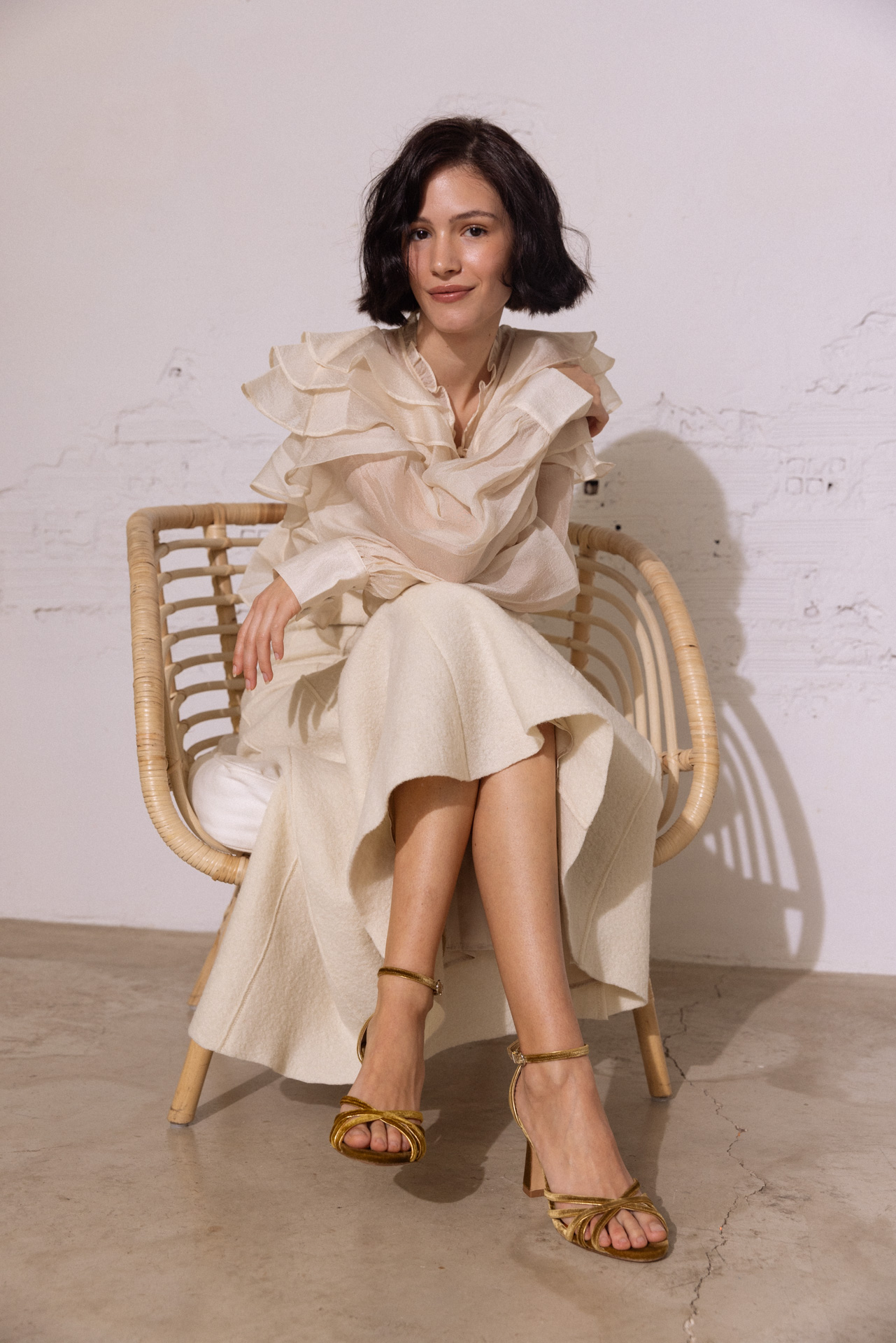 Novia sentada elegante con las piernas cruzadas, destacando su zapato modelo Lou en color ambar de Flordeasoka, epitomizando la elegancia y el diseño contemporáneo.