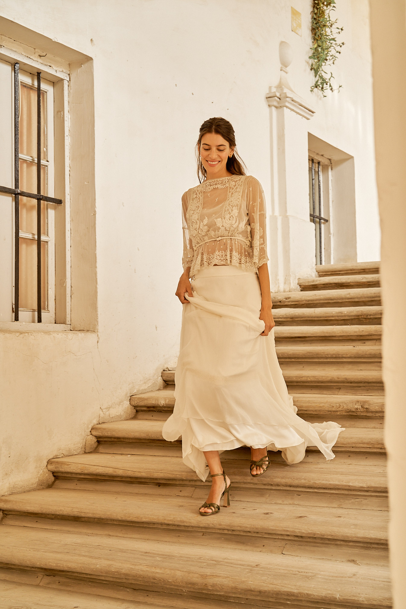 Novia elegante bajando escalones luciendo su vestido de novia y zapatos metalizados de Flordeasoka, destacando la combinación perfecta de tradición y tendencia.