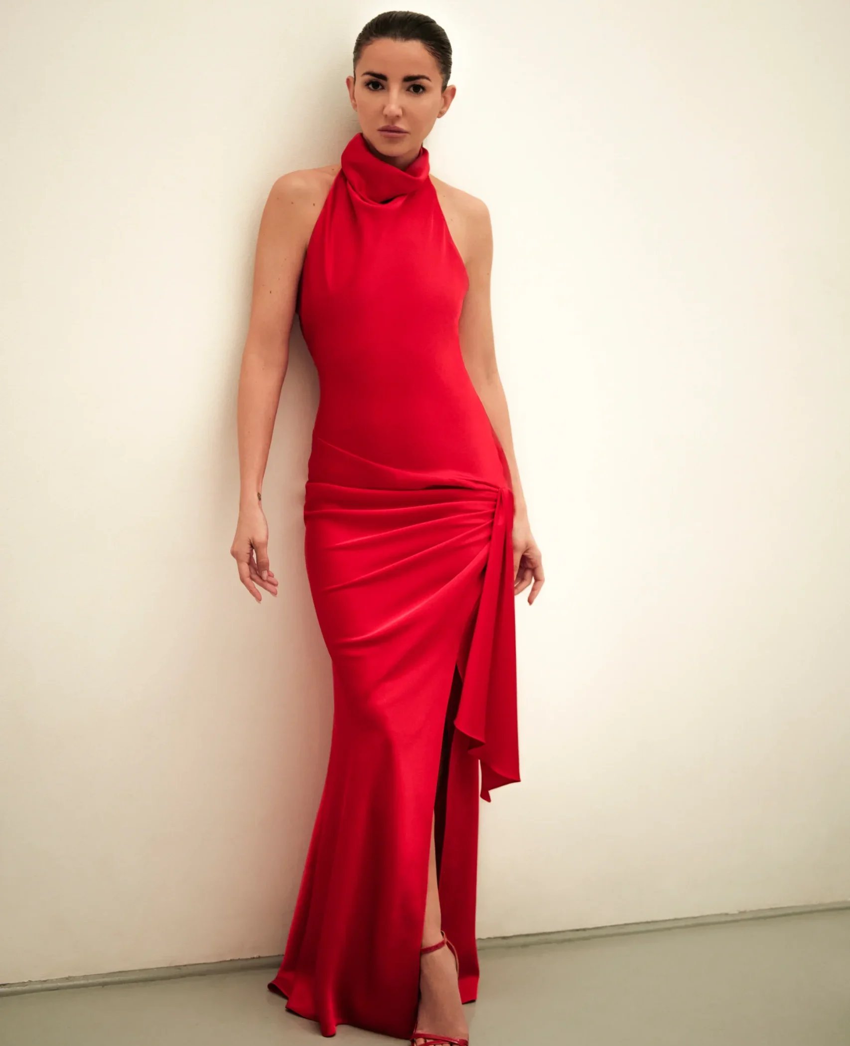 Vestido largo rojo de crepe satén con escote halter, espalda descubierta y abertura lateral.