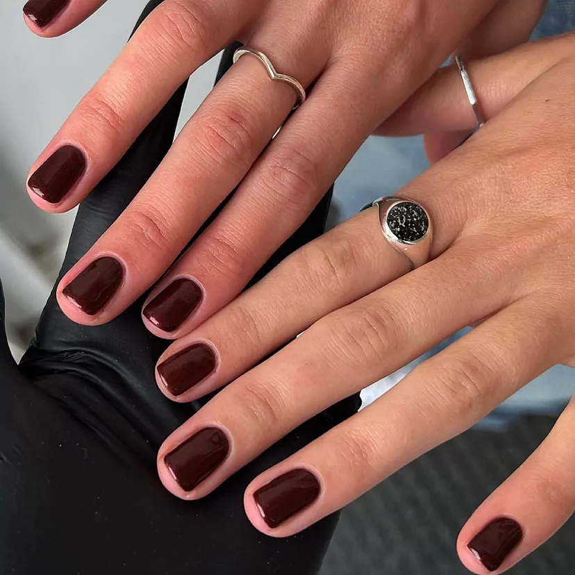 Primer plano de uñas con manicura en tonos burdeos para novia, sofisticación y distinción.