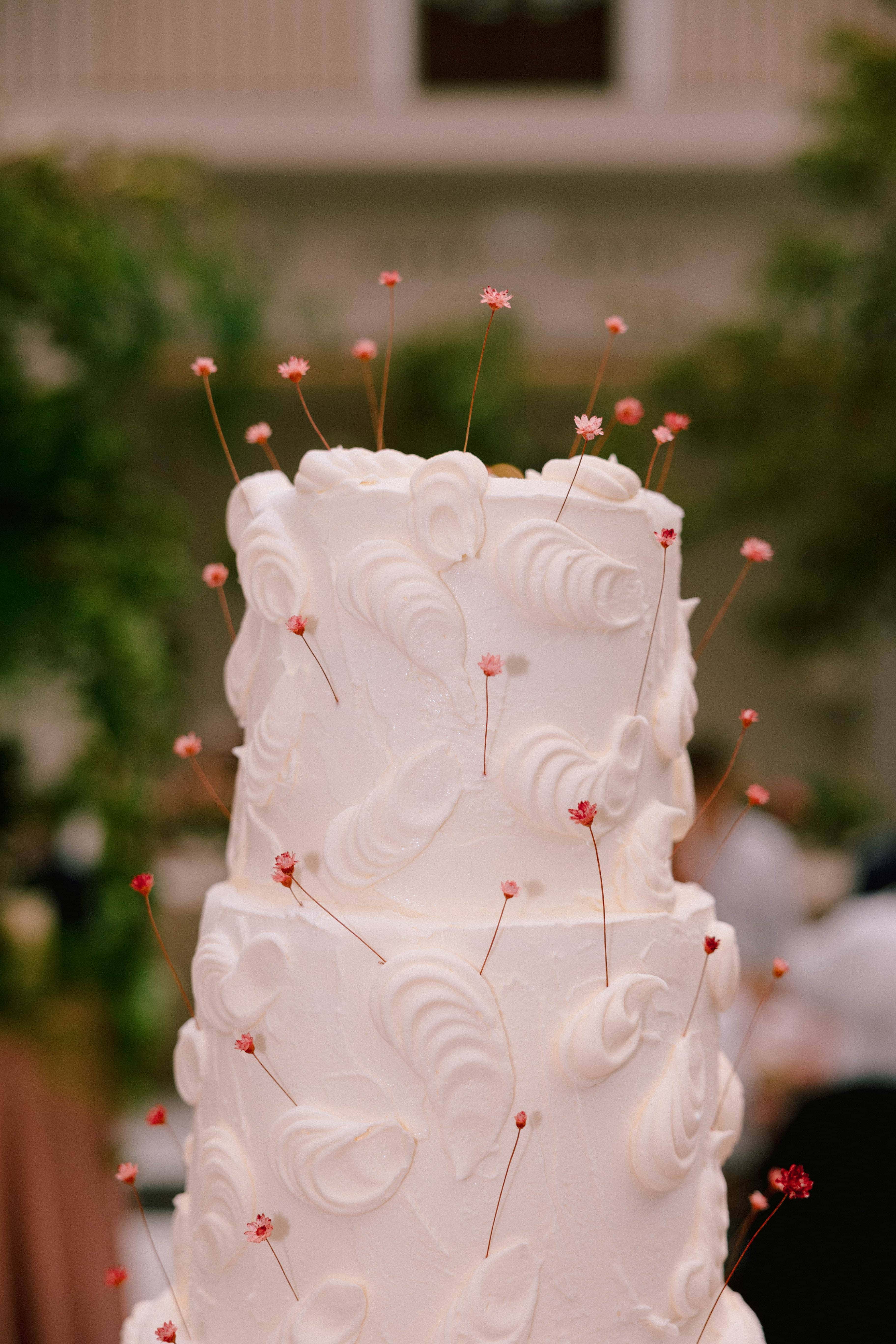 Pastel de boda blanco de tres pisos con decoración elegante, símbolo de grandeza en las tendencias de boda 2025.