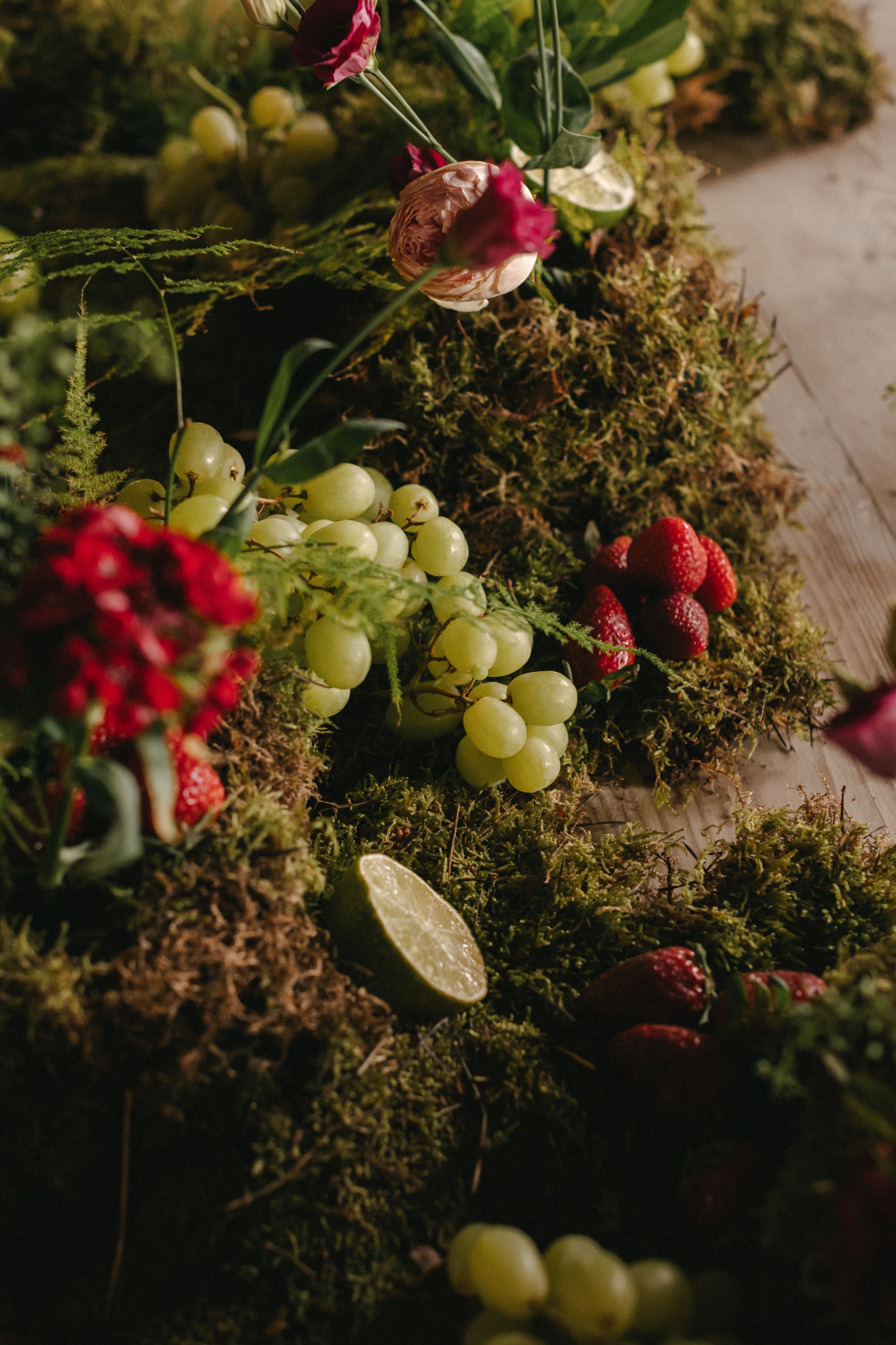 Decoración de boda con musgo, uvas y limas como centro de mesa, siguiendo las tendencias de boda 2025.