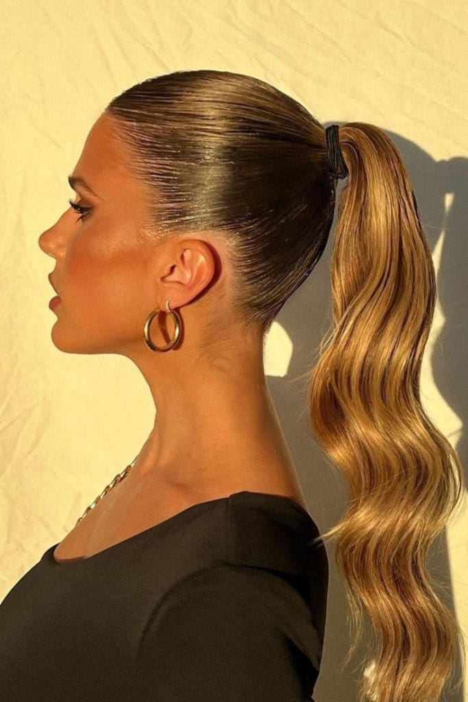 Coleta alta elegante y versátil para invitadas de boda, con opción lisa o con ondas.