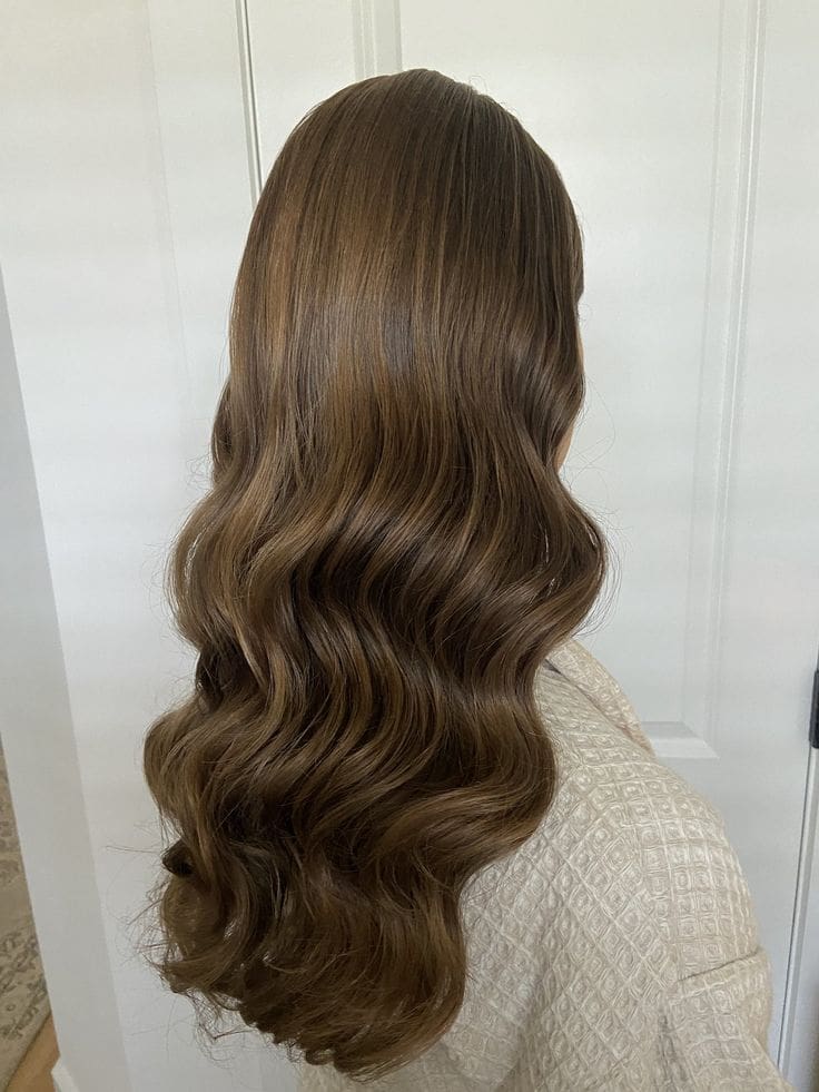 Peinado de invitada de boda con cabello suelto y ondas suaves, decorado con accesorios.