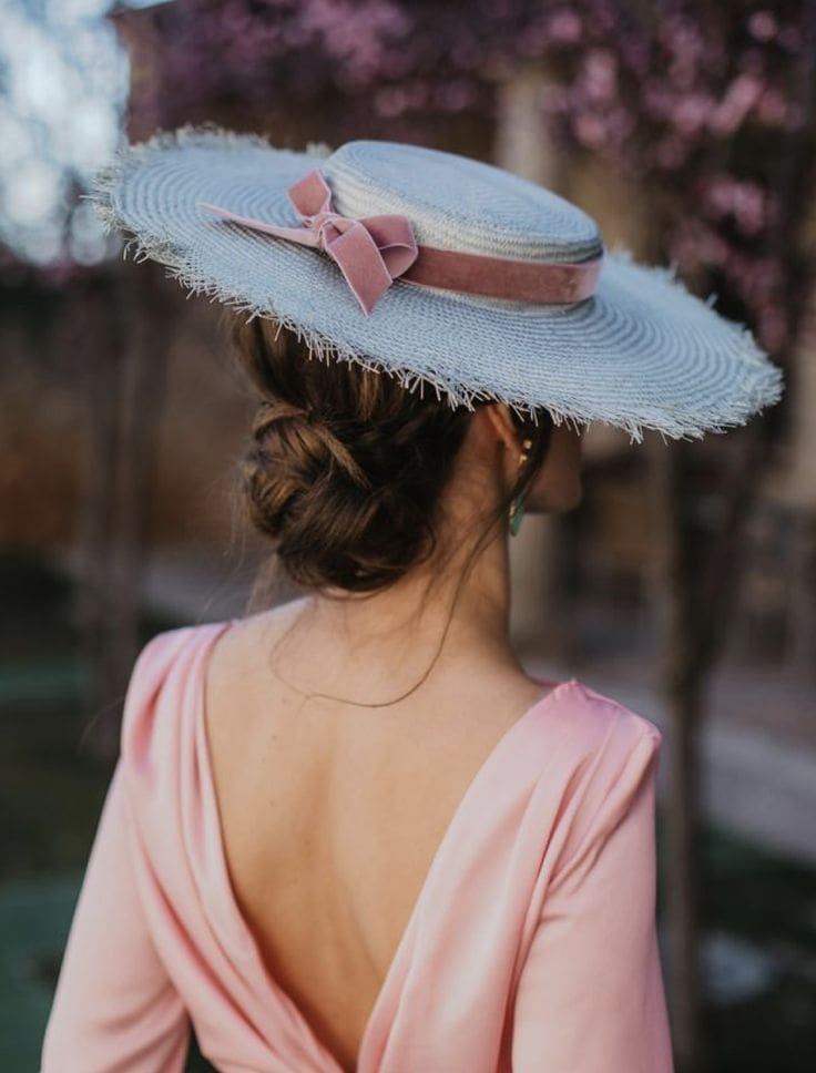 Recogido bajo elegante para invitadas de boda que llevan pamela como accesorio.