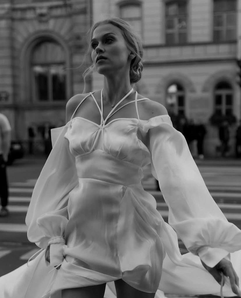 Primer plano de una novia con un vestido de seda de corte romántico, caminando entre calles urbanas.