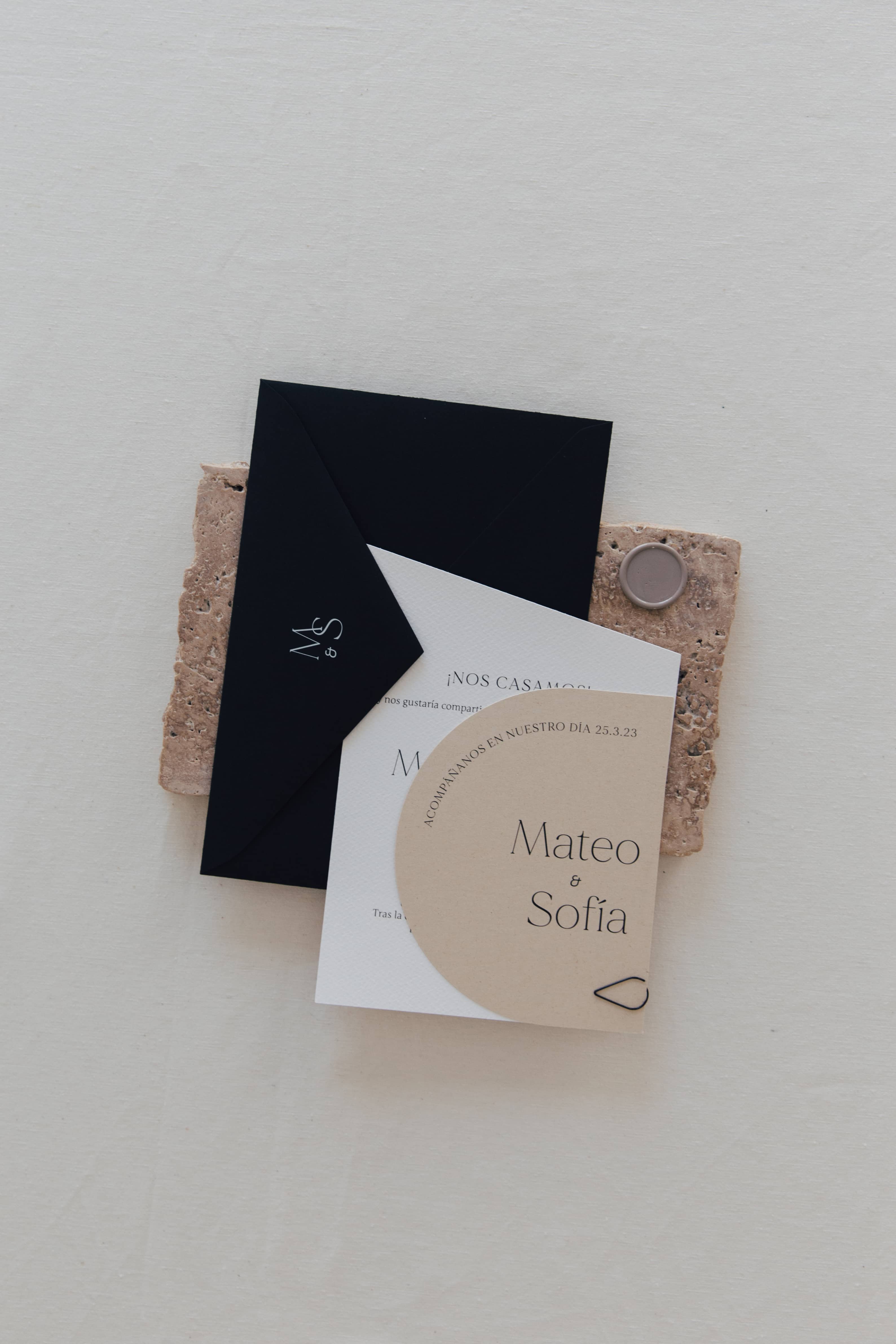 Invitación de boda en tonos beige y negro con sobre oscuro y sellado en cera.