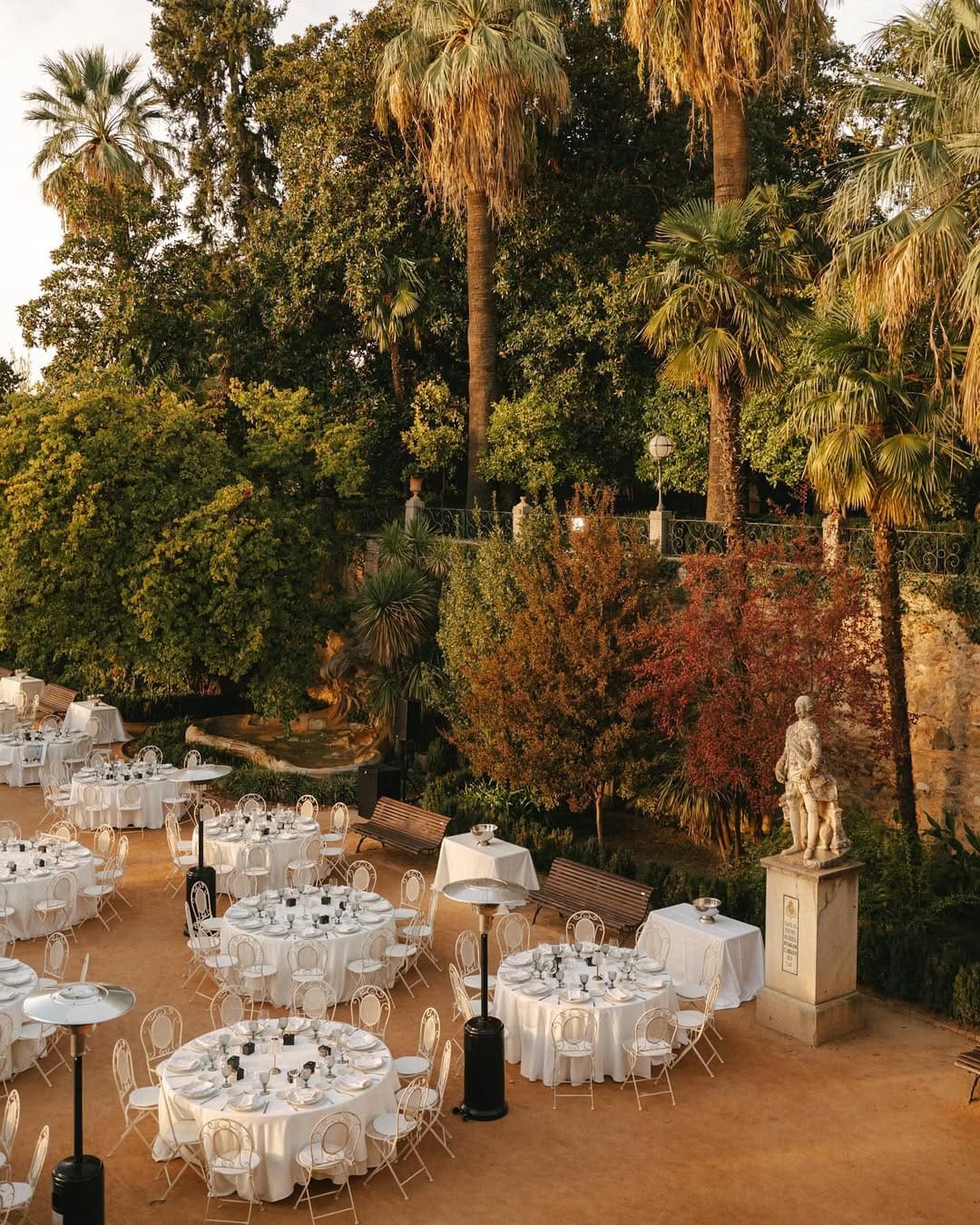 Banquete de boda al aire libre con mesas redondas elegantemente decoradas.