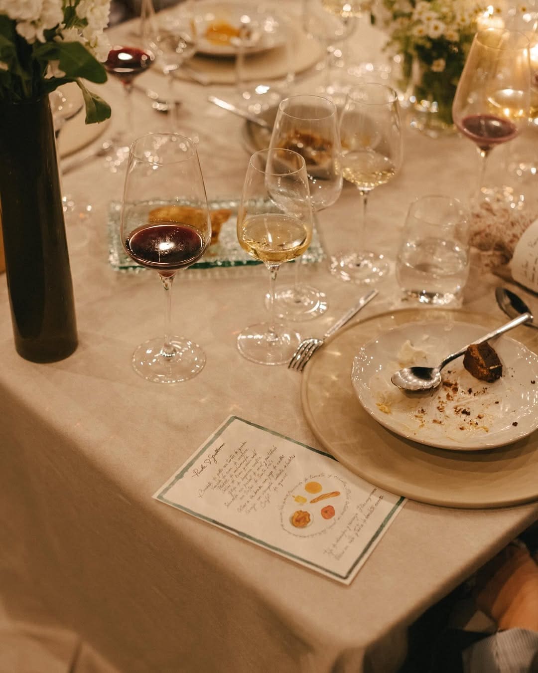 Mesa de boda con copas de vino, platos y un menú elegante.